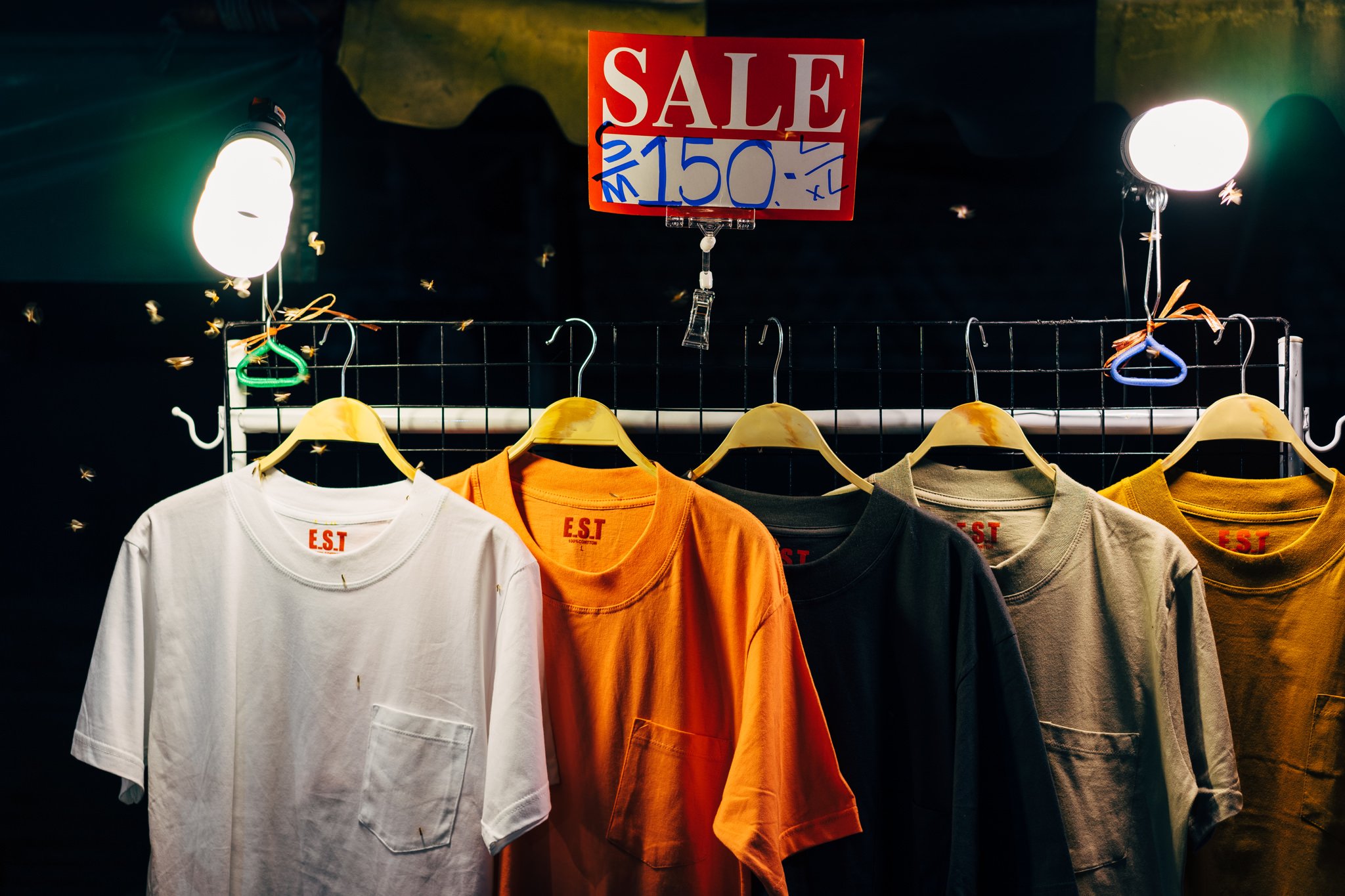 T-shirts on sale for ฿150 at a Bangkok night market.