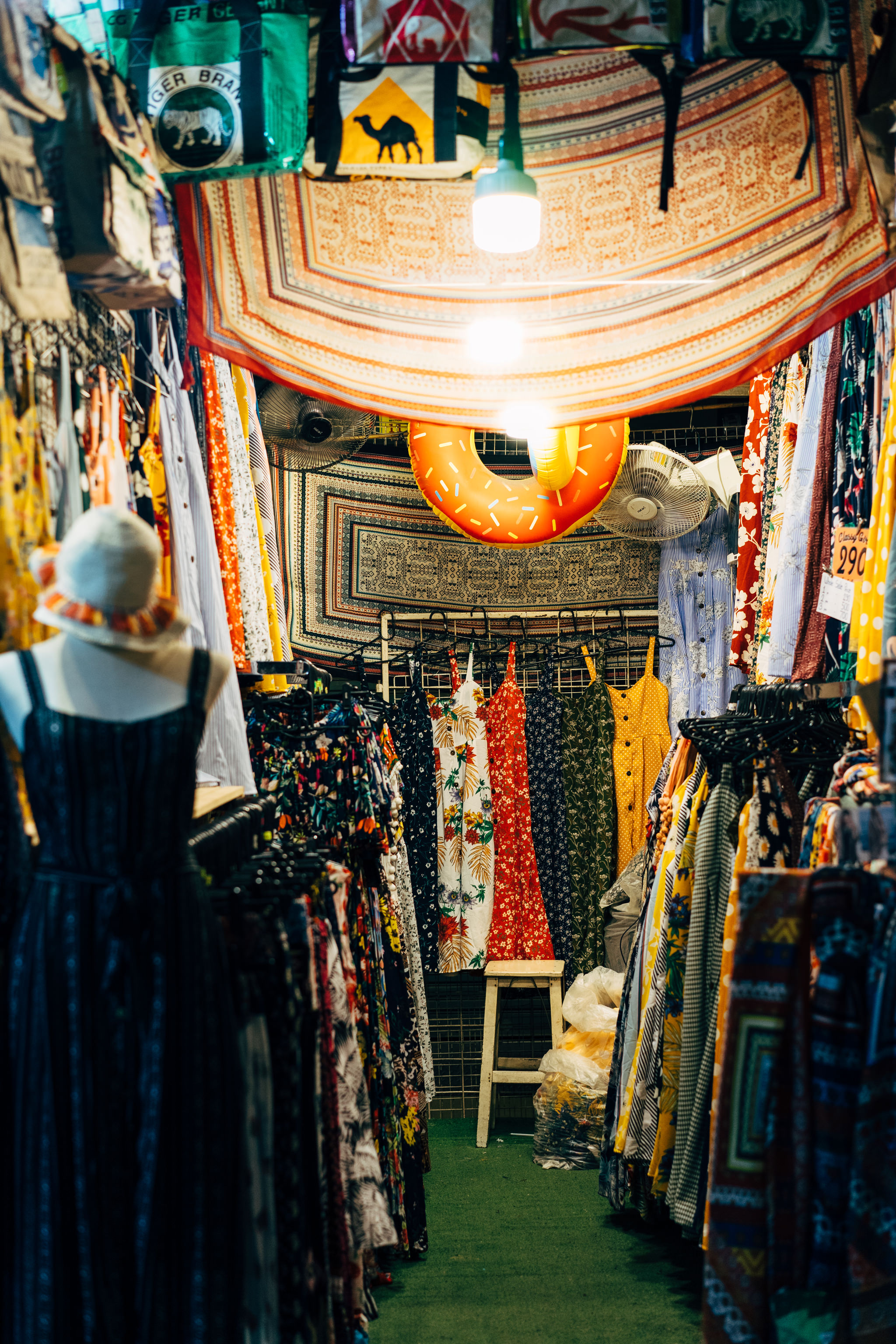 Bangkok market clothing stall with colorful dresses and fabrics.