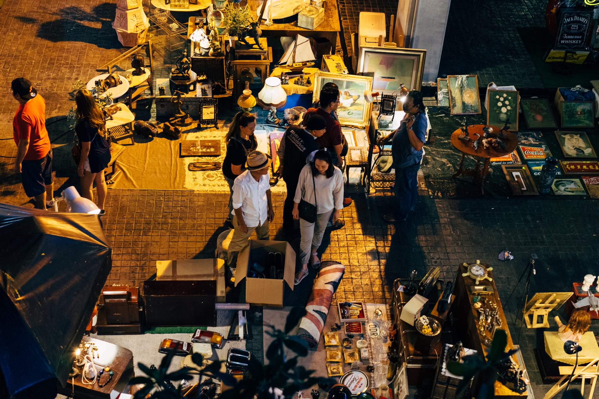 Aerial view of a Bangkok night flea market with vendors and customers browsing various antiques and collectibles.