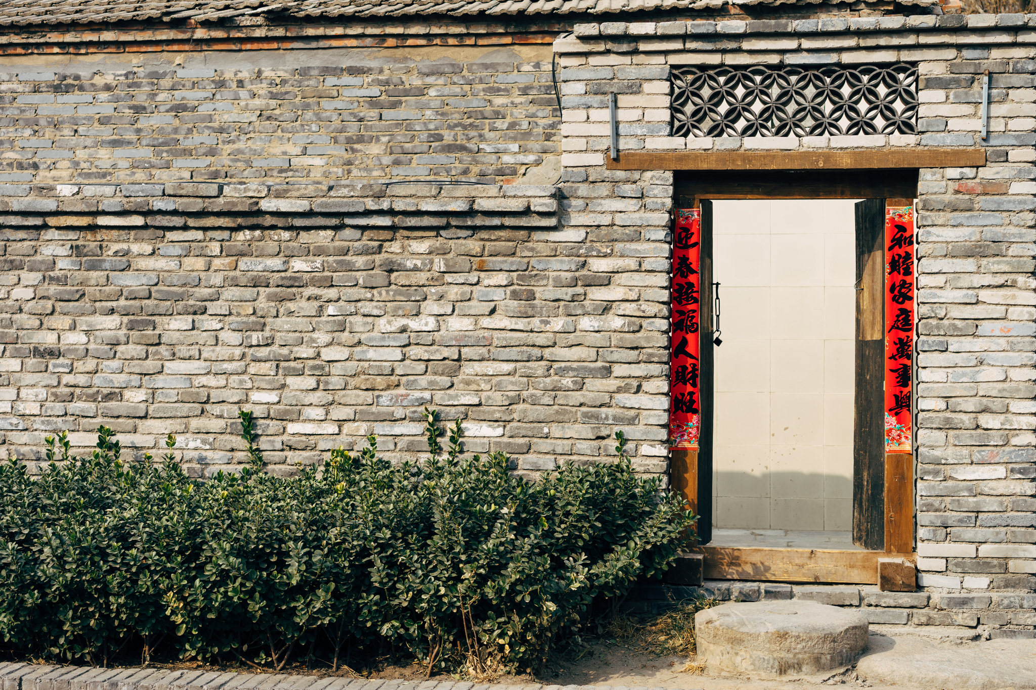 Beijing neighborhood entrance with brick wall and wooden door.