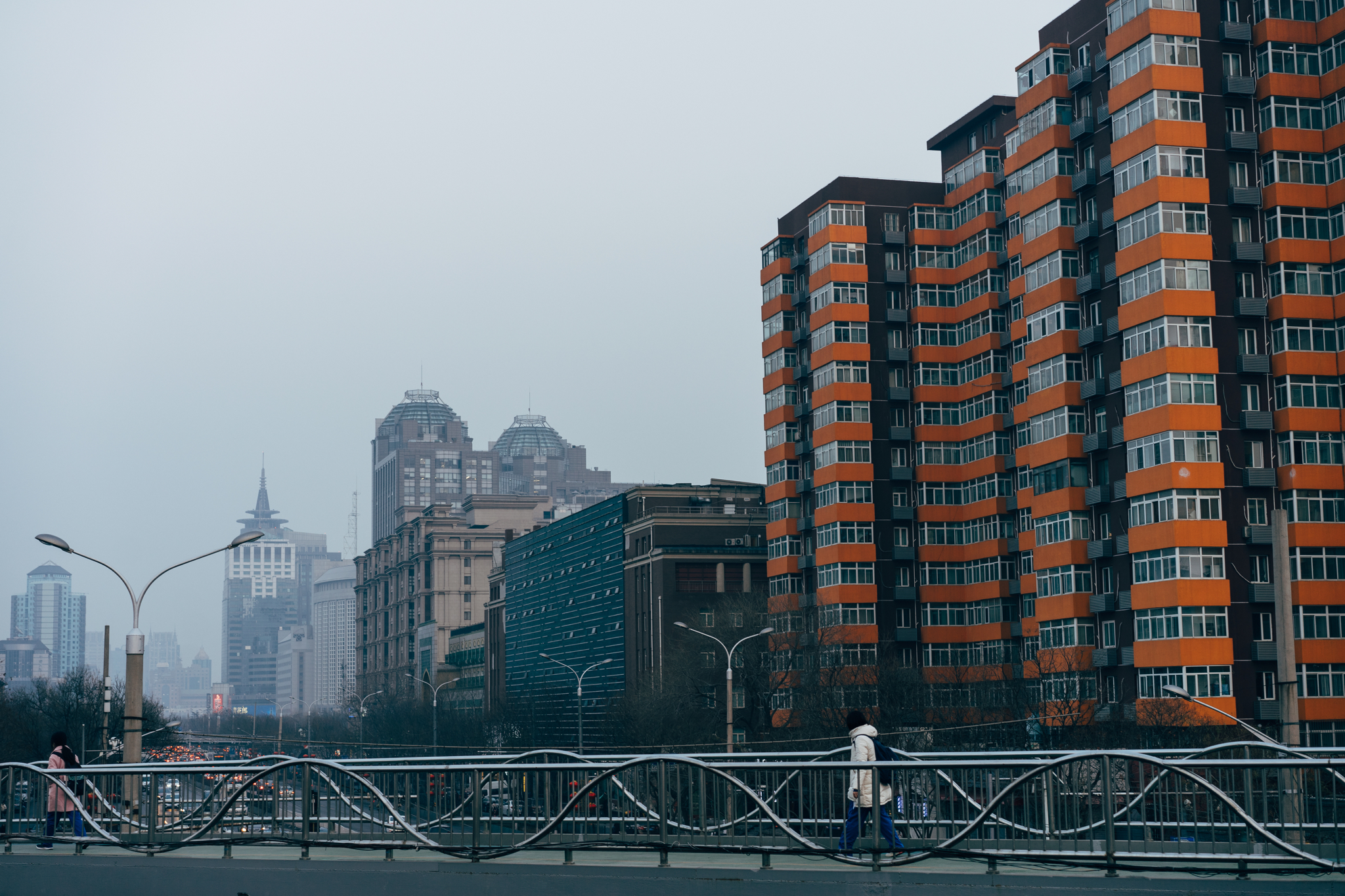 Beijing cityscape with pedestrians on a bridge and residential buildings.