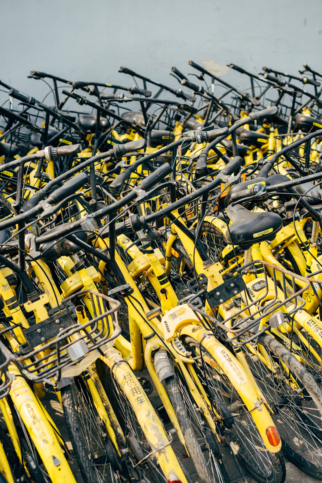 A pile of discarded, yellow, and weathered shared bicycles in China.