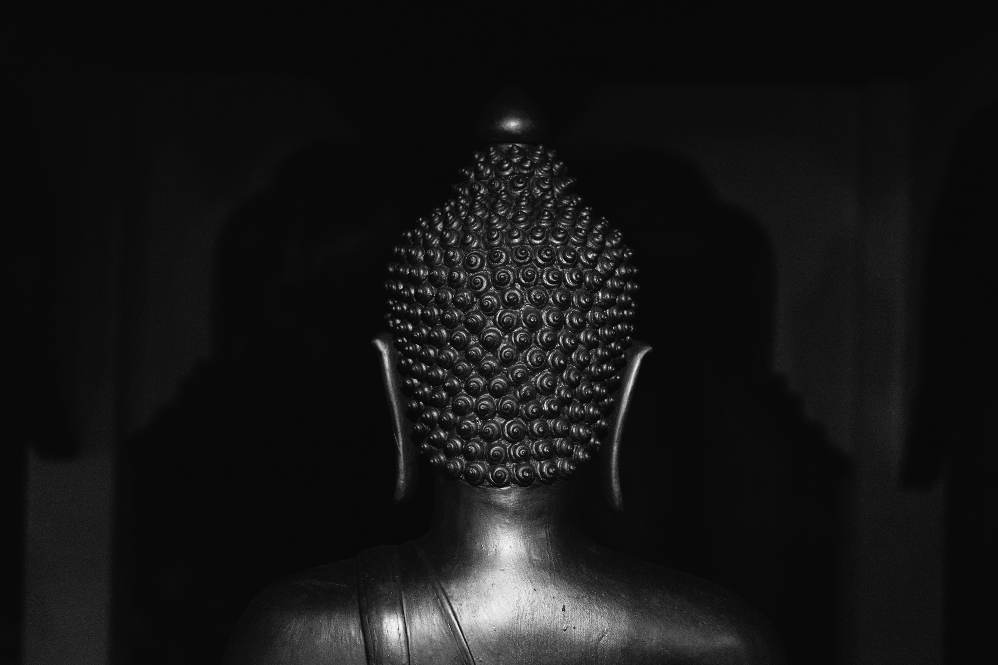Rear view of a dark-colored Buddha statue.