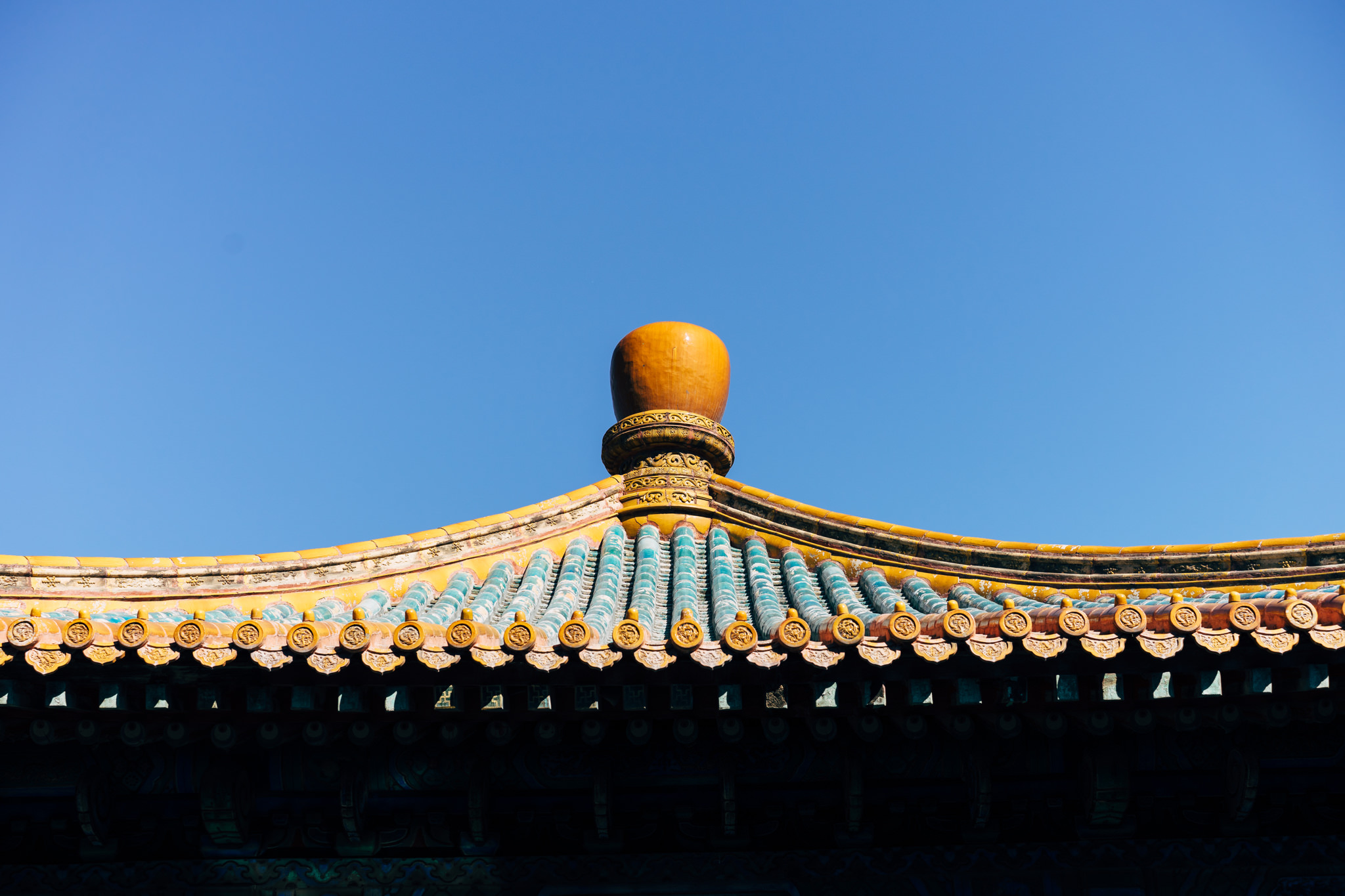Ornate Forbidden City rooftop detail with yellow and teal glazed tiles.