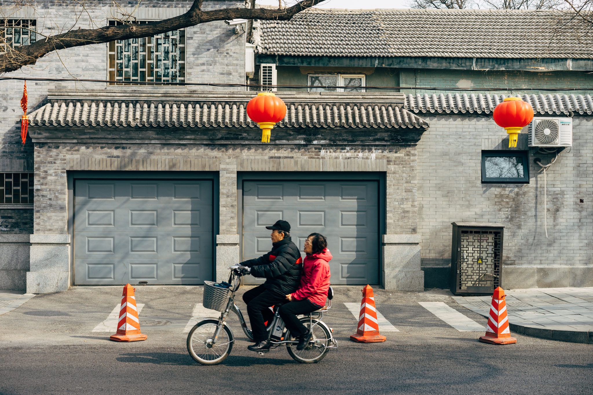Older couple riding an electric bike in Beijing.