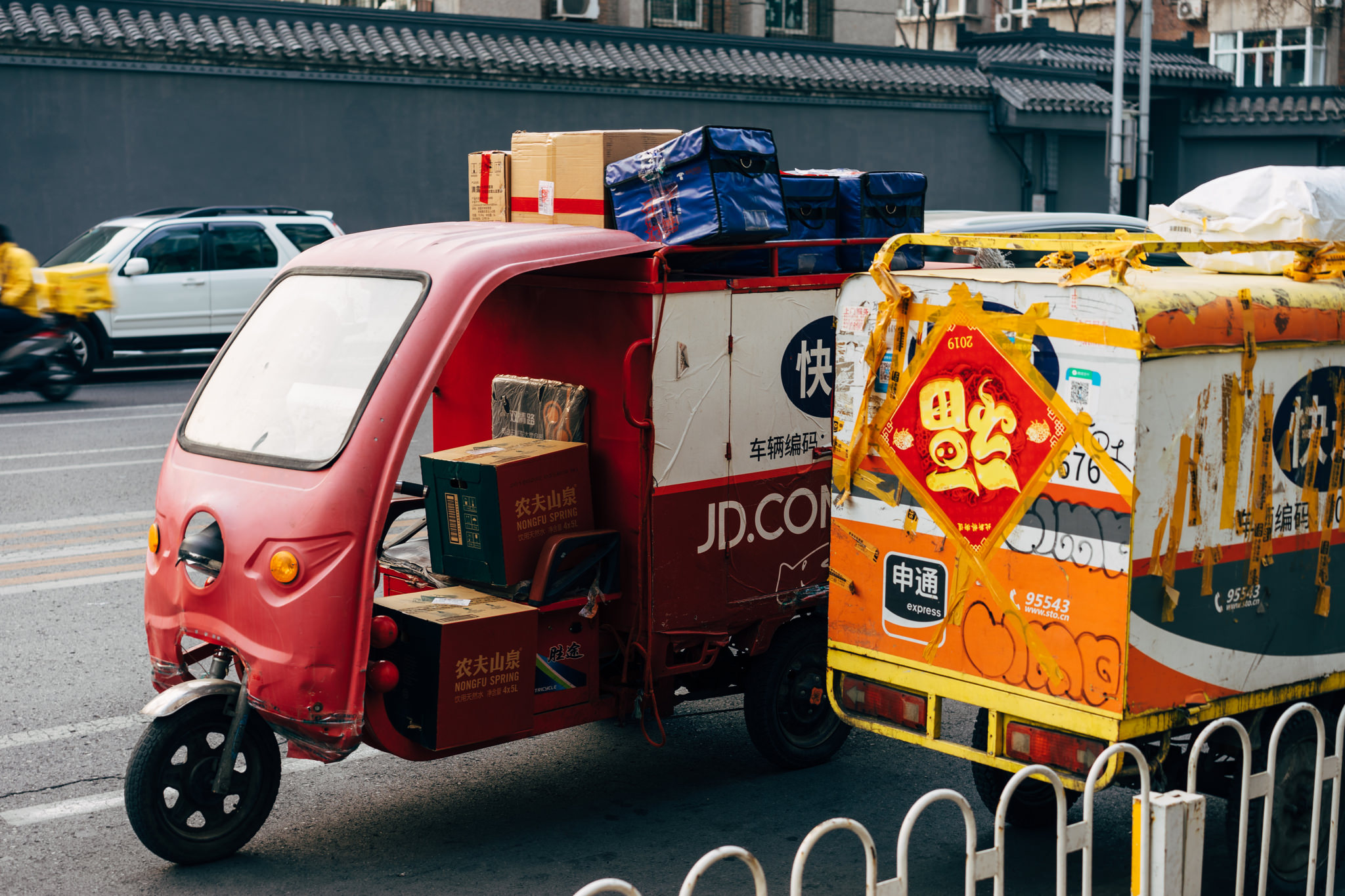 JD.com delivery truck and another delivery vehicle loaded with packages in Beijing.