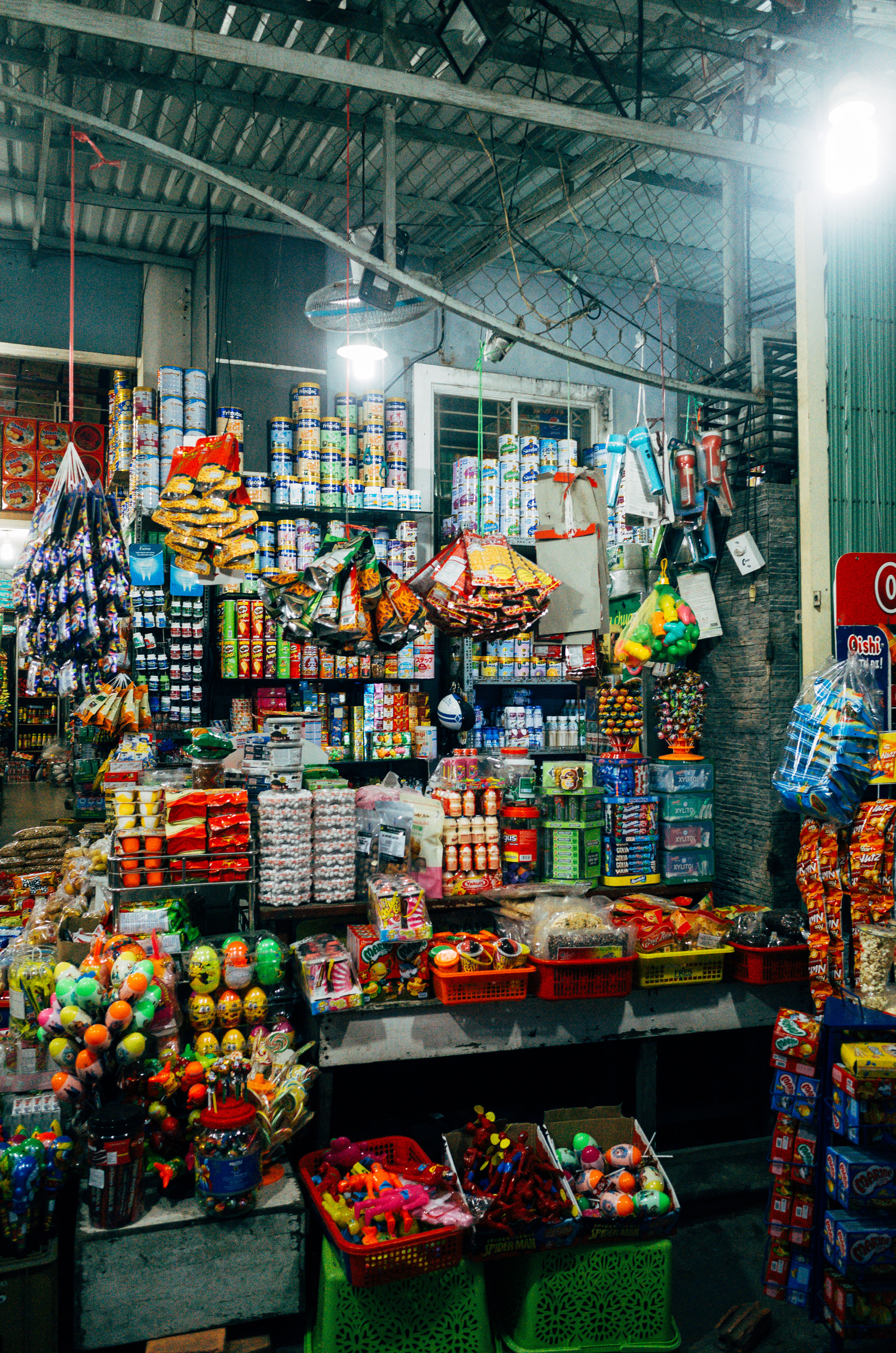 A brightly lit Hoi An shop stocked with shelves of snacks, candies, and various goods.