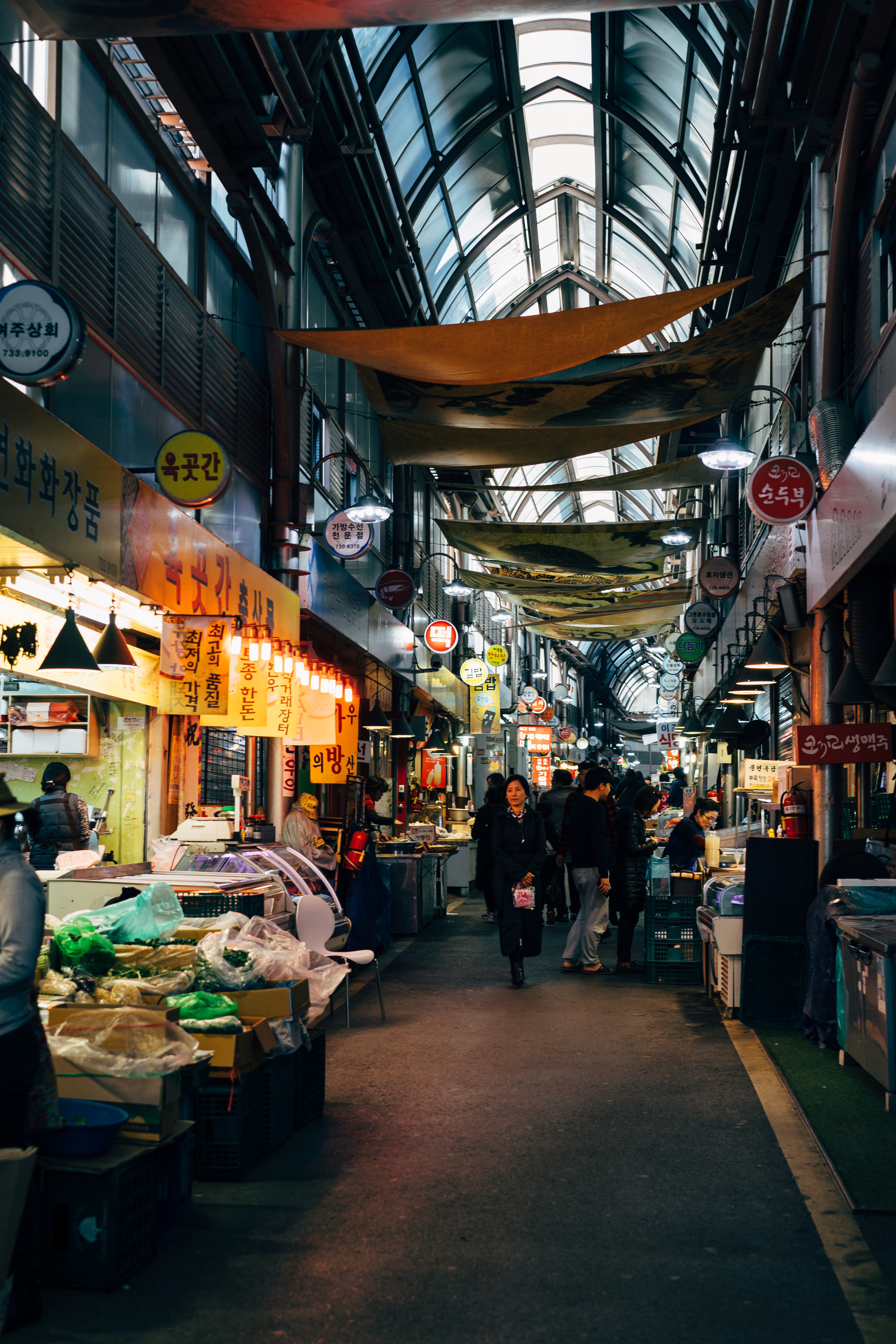 Interior of a bustling Korean market, with vendors and shoppers.