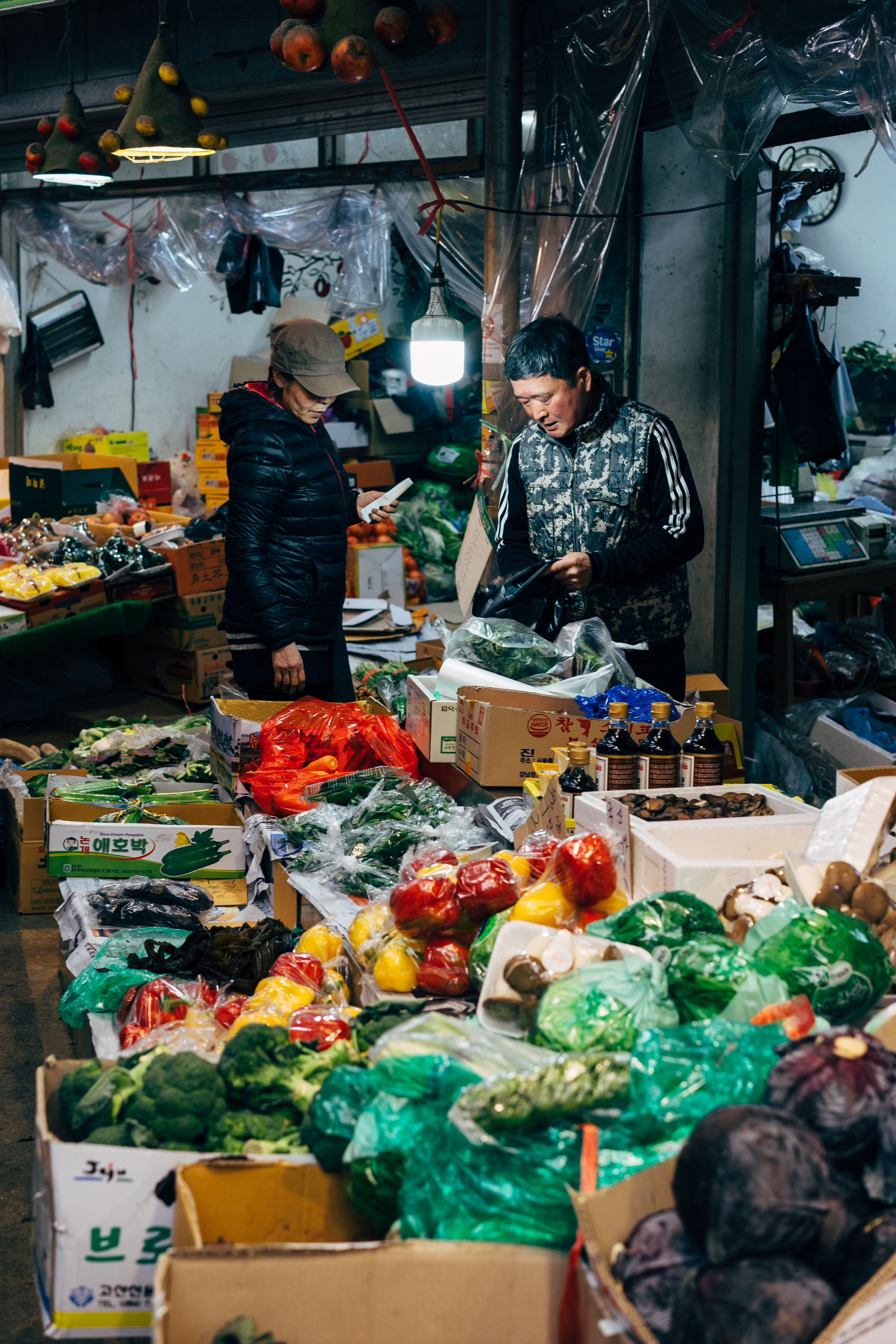 Two people shopping for produce in a Korean market.
