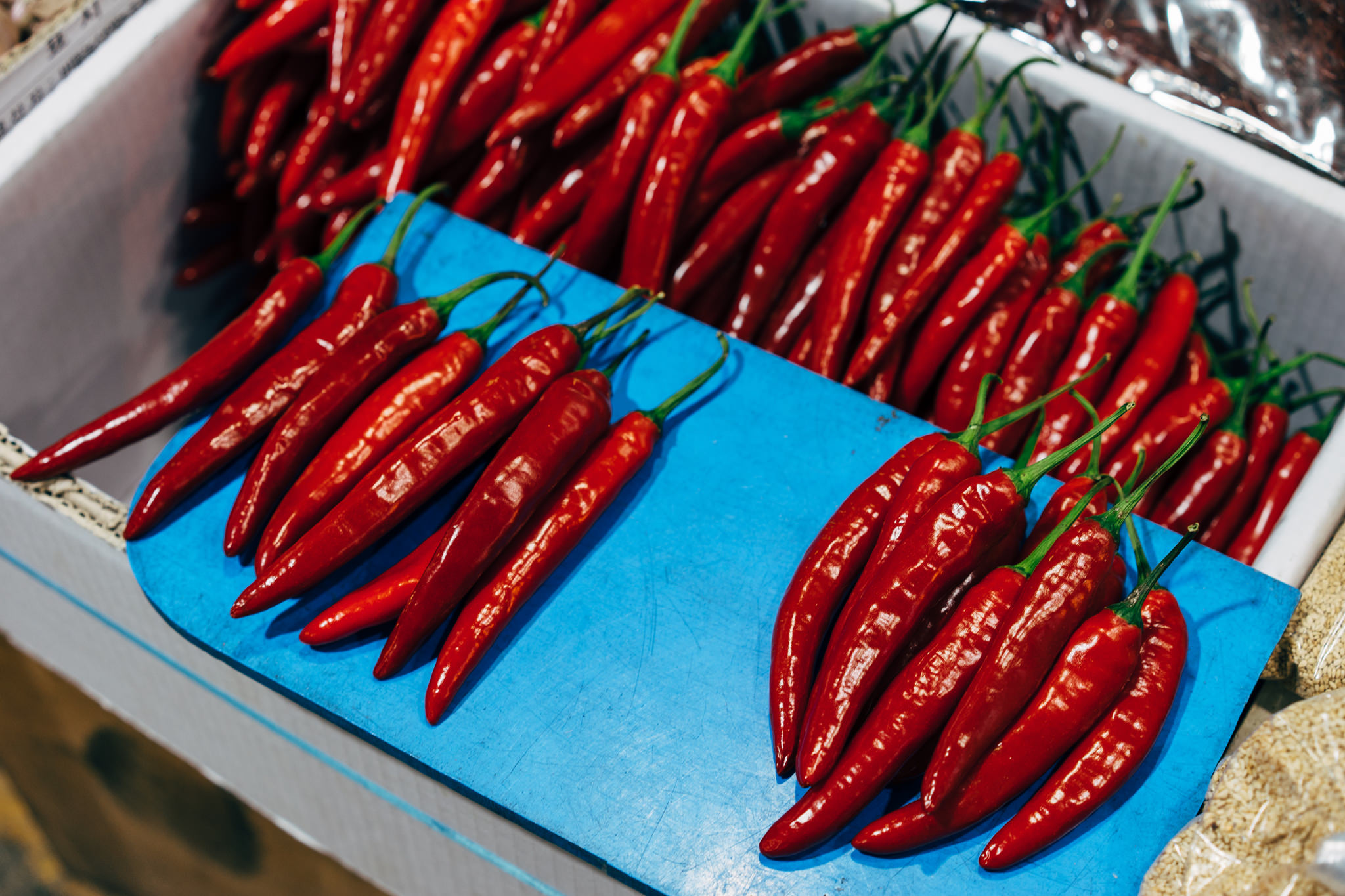 Red chili peppers on a blue cutting board in a market.