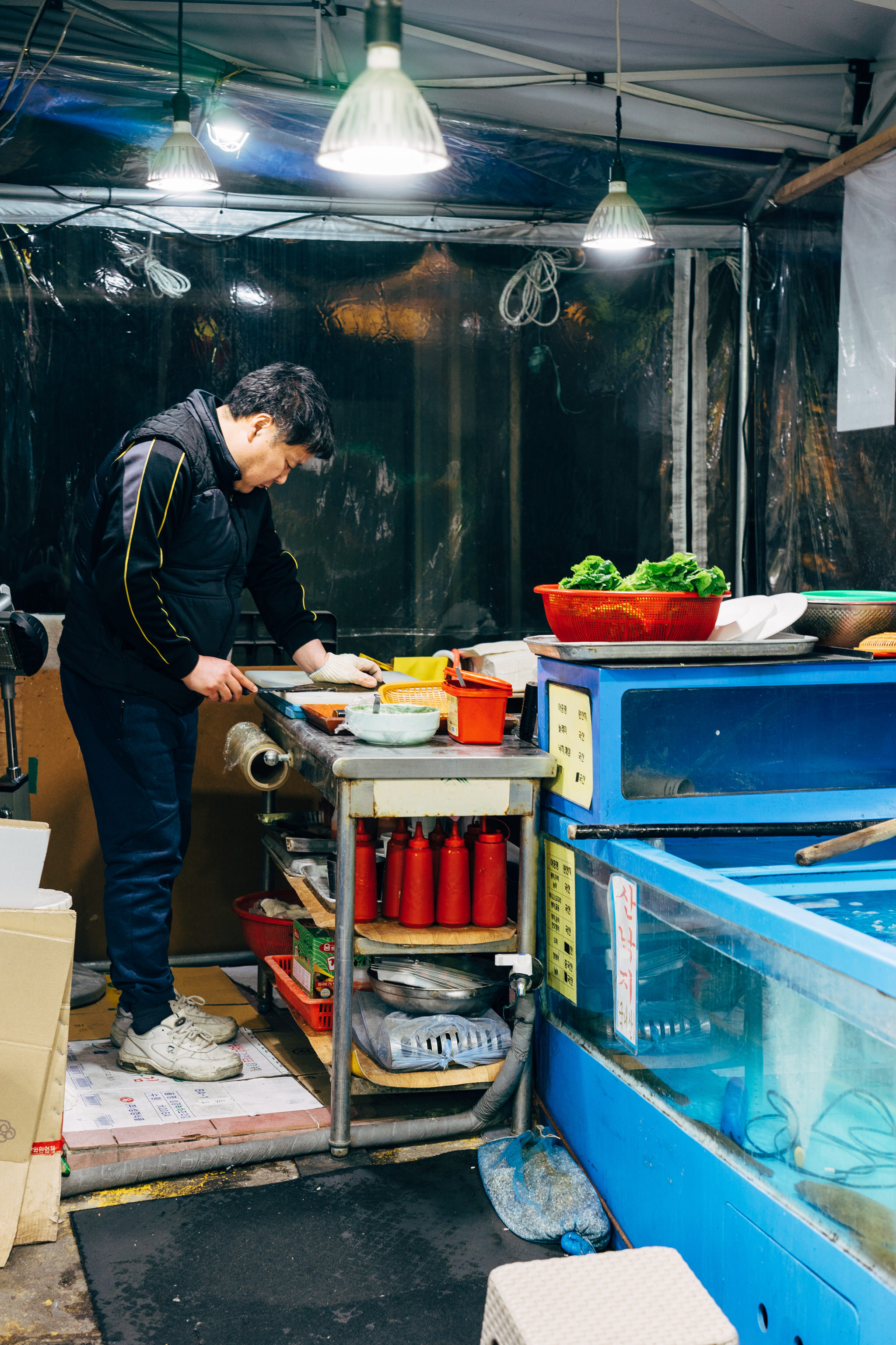 A person preparing food in a Korean fish market.