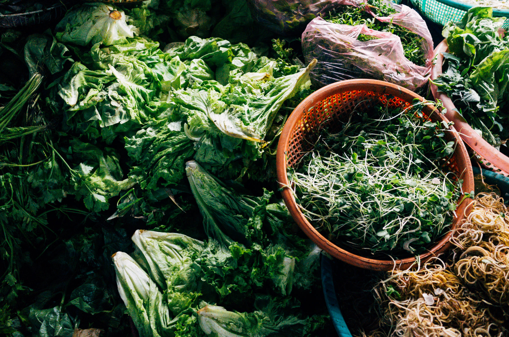Overhead view of various green vegetables at a Vietnamese market.