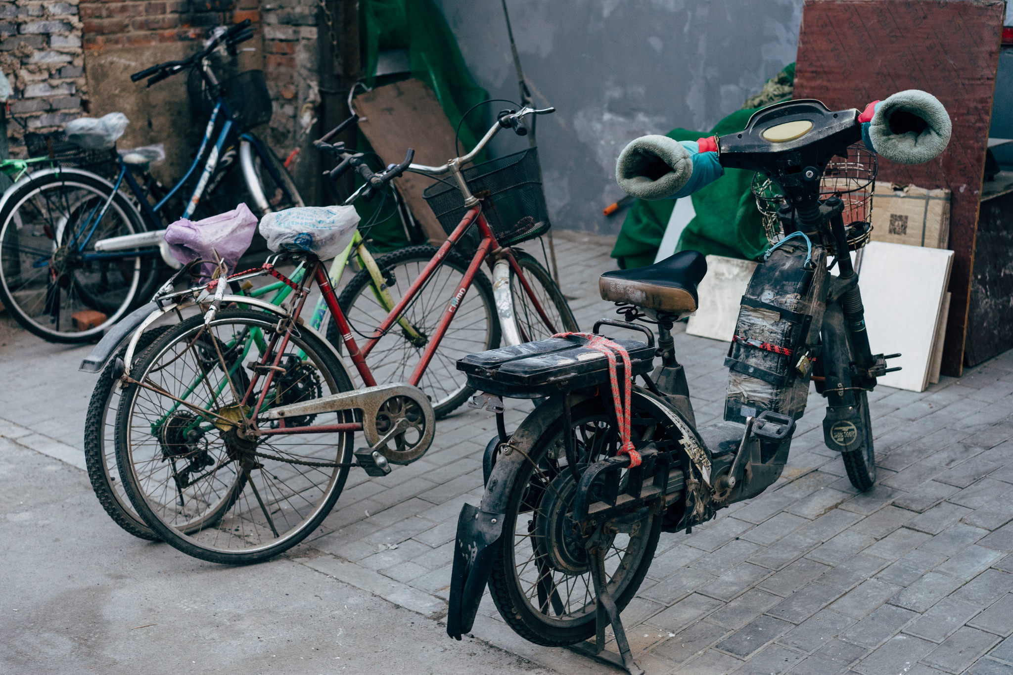 Three bicycles and a moped parked together.