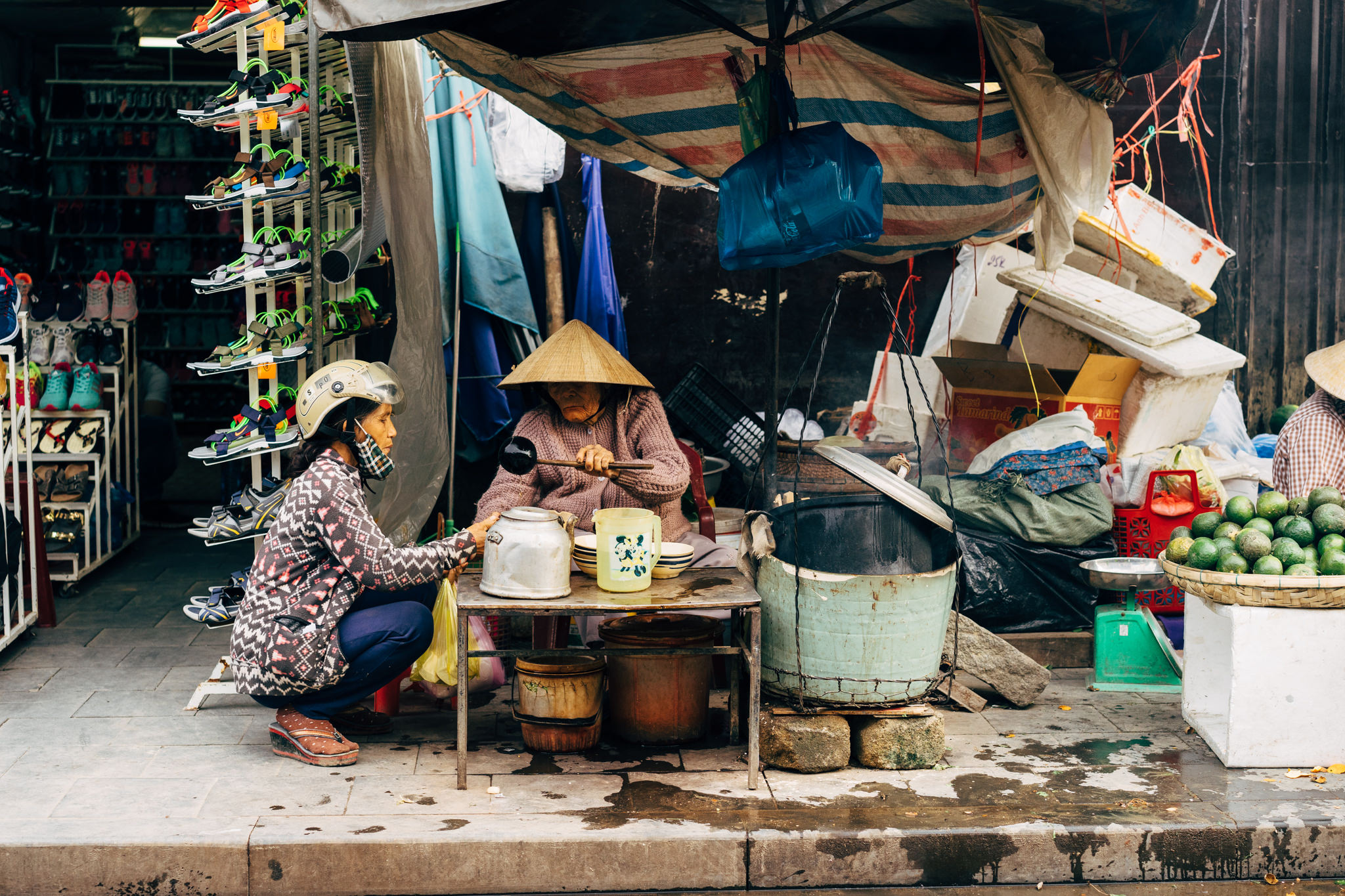Two women selling food from a makeshift stall on a city street.