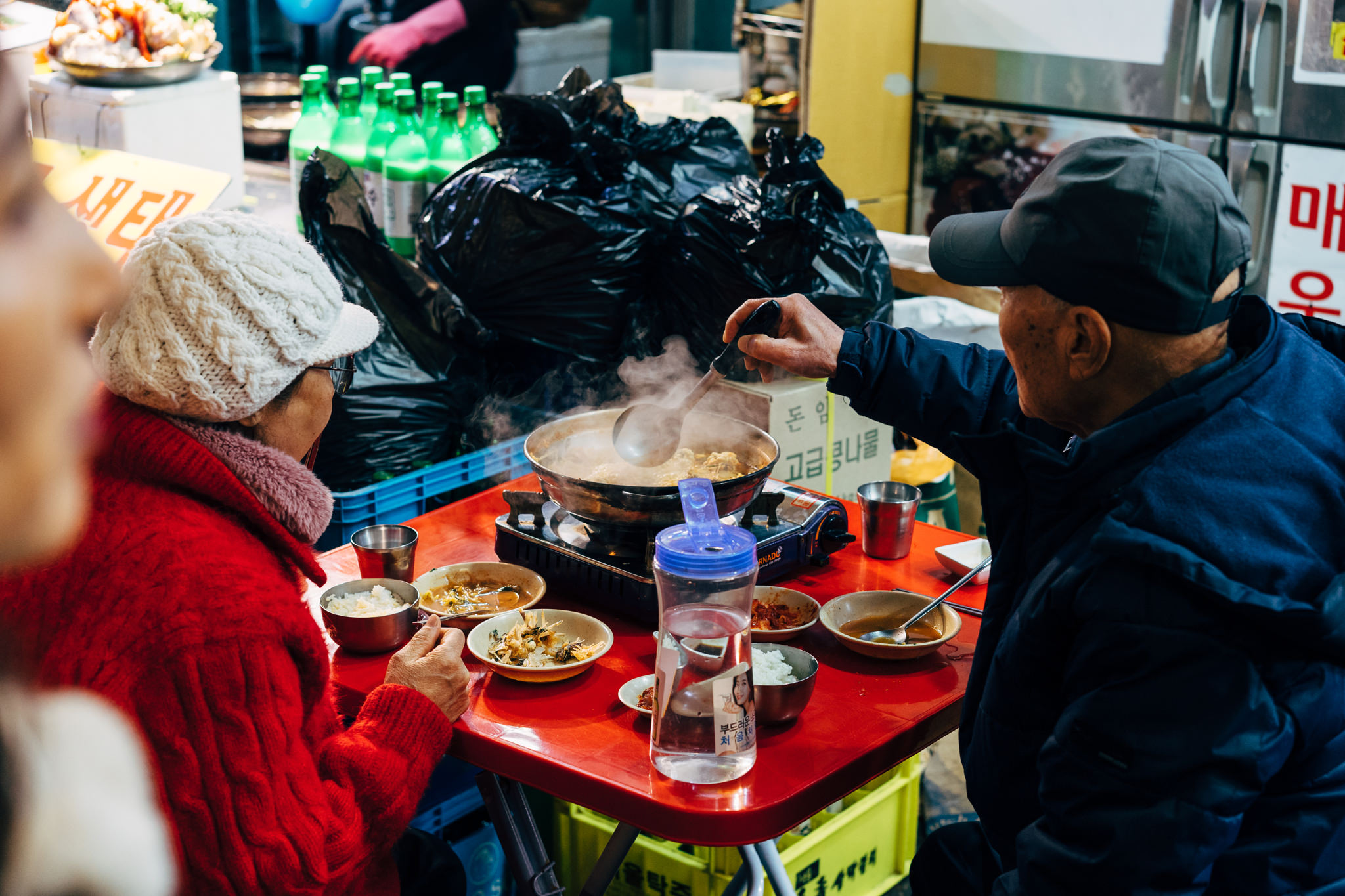 Two people eating at a table in a Seoul food market.