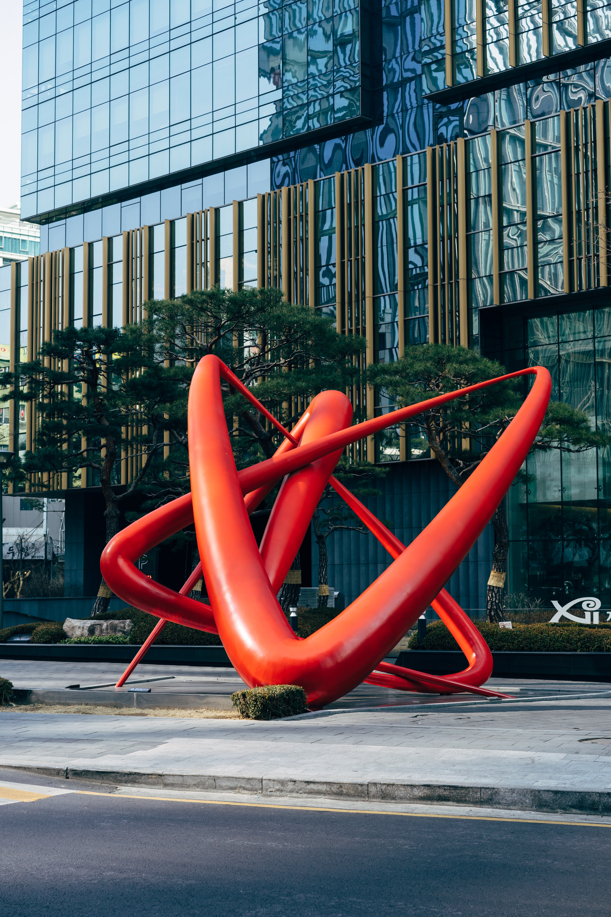 Large red abstract sculpture in front of modern building in Seoul, South Korea.