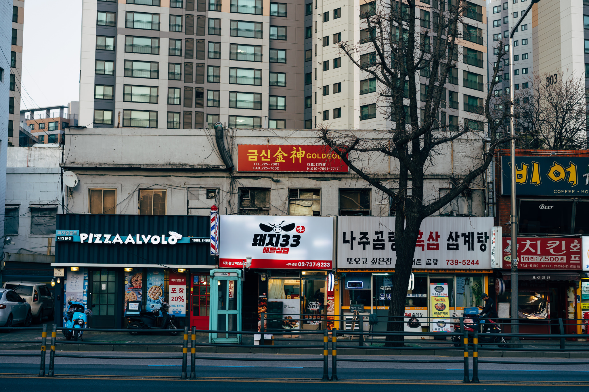 Seoul street scene with shops and apartment buildings.