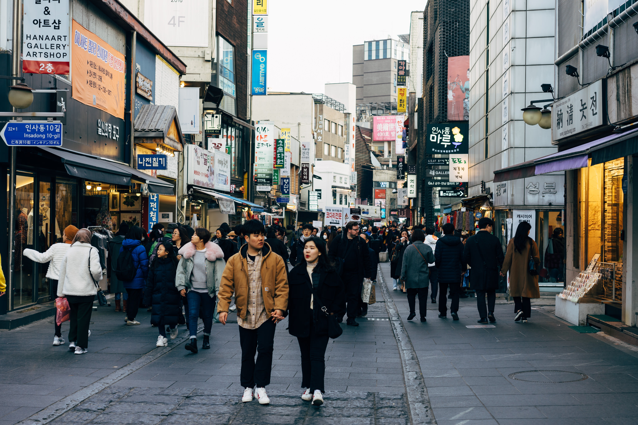 Crowded street scene in Seoul, South Korea, with shops and people walking.