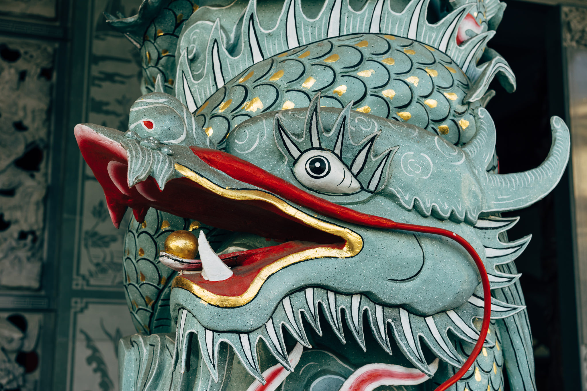 Close-up of a teal and red painted dragon statue head.