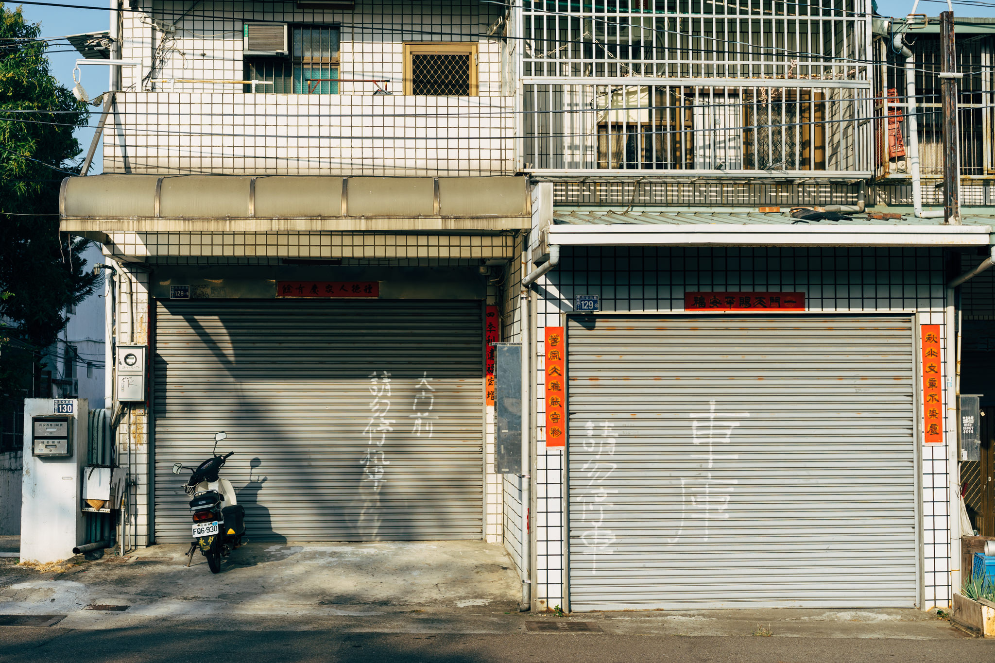 Scooter parked in front of two closed roll-up garage doors with Chinese characters painted on them.