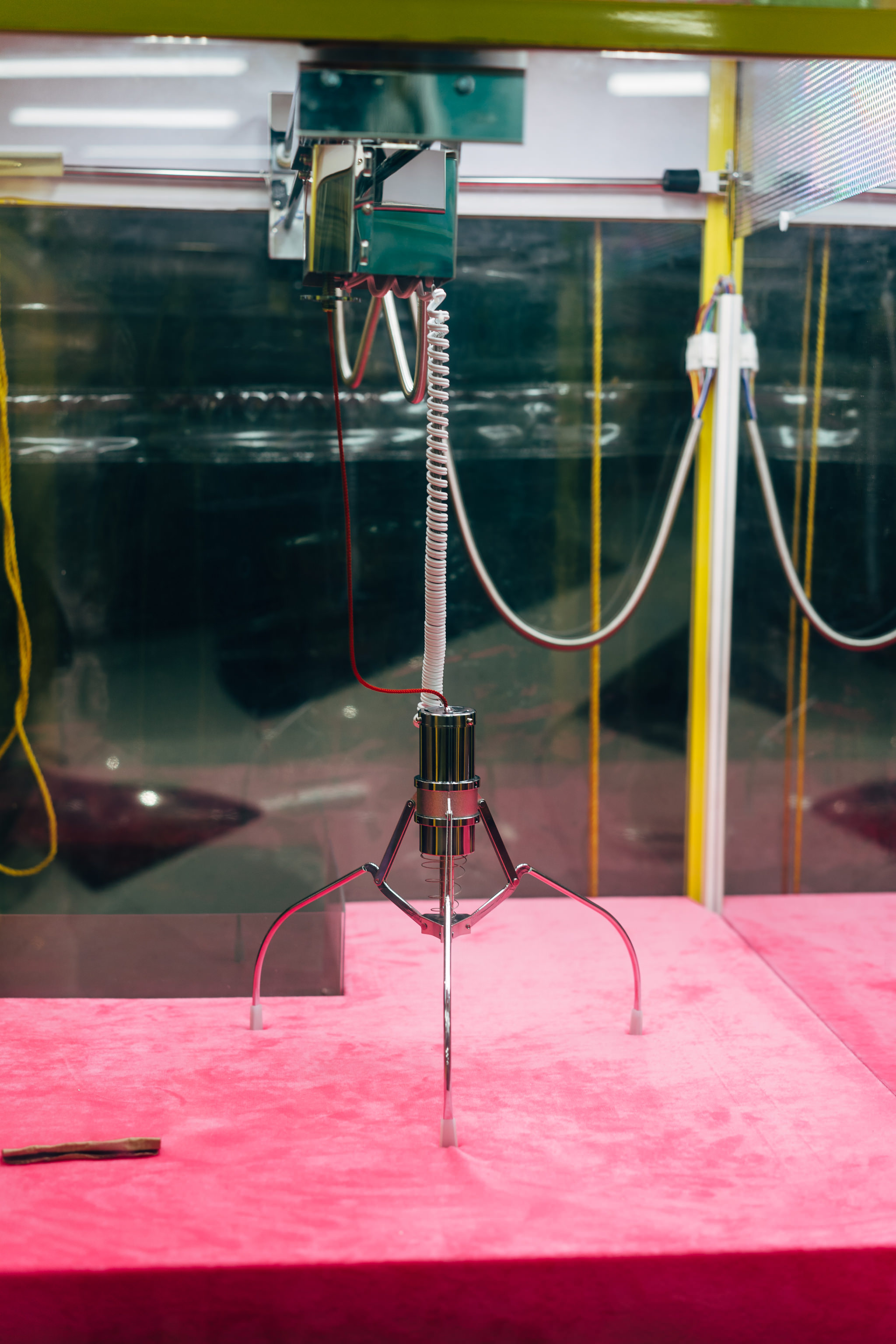 Claw machine crane on pink surface.
