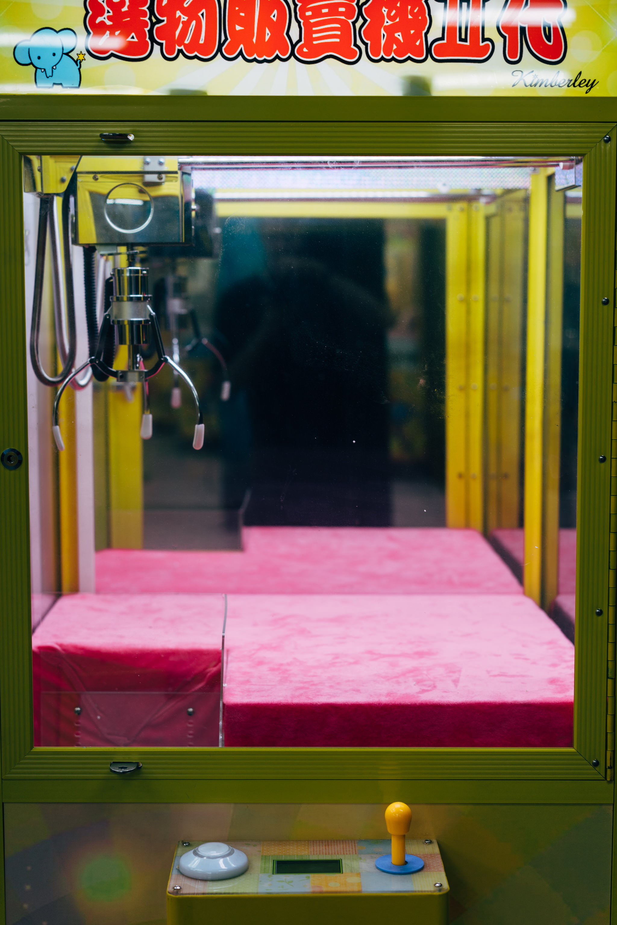 Claw machine with pink interior and yellow exterior.