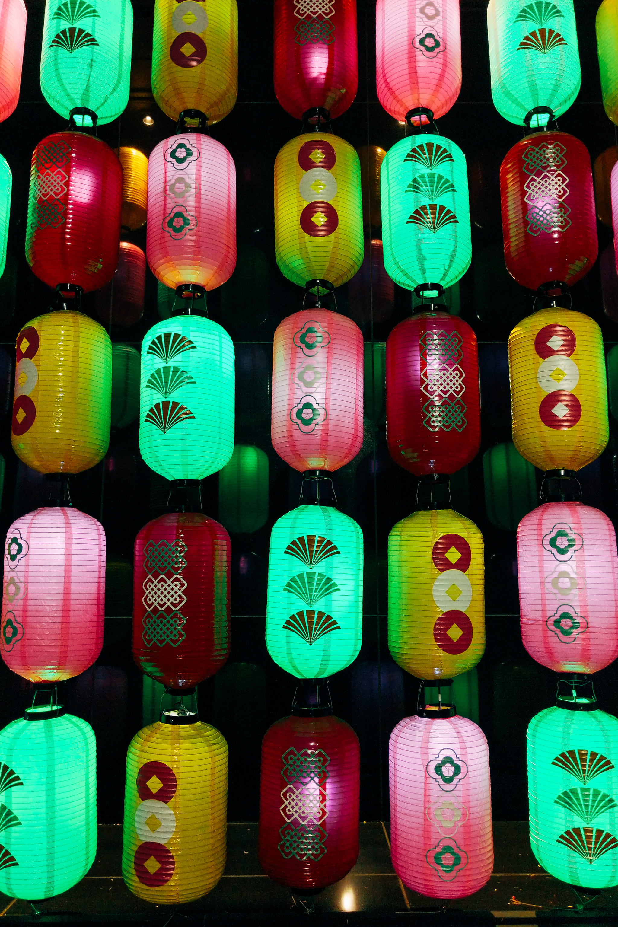 Wall of illuminated lanterns with various Asian-inspired designs.