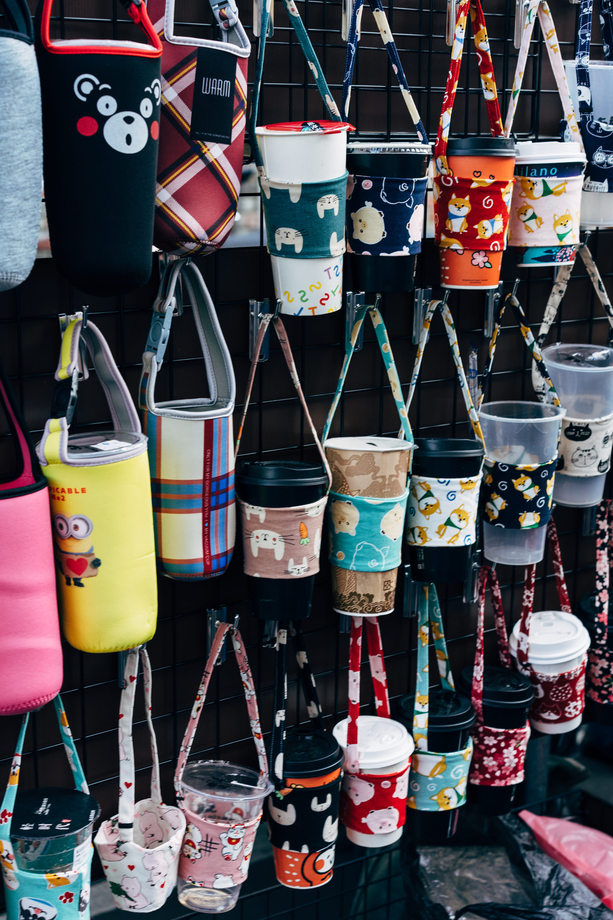 Many patterned beverage holders hanging on a rack.