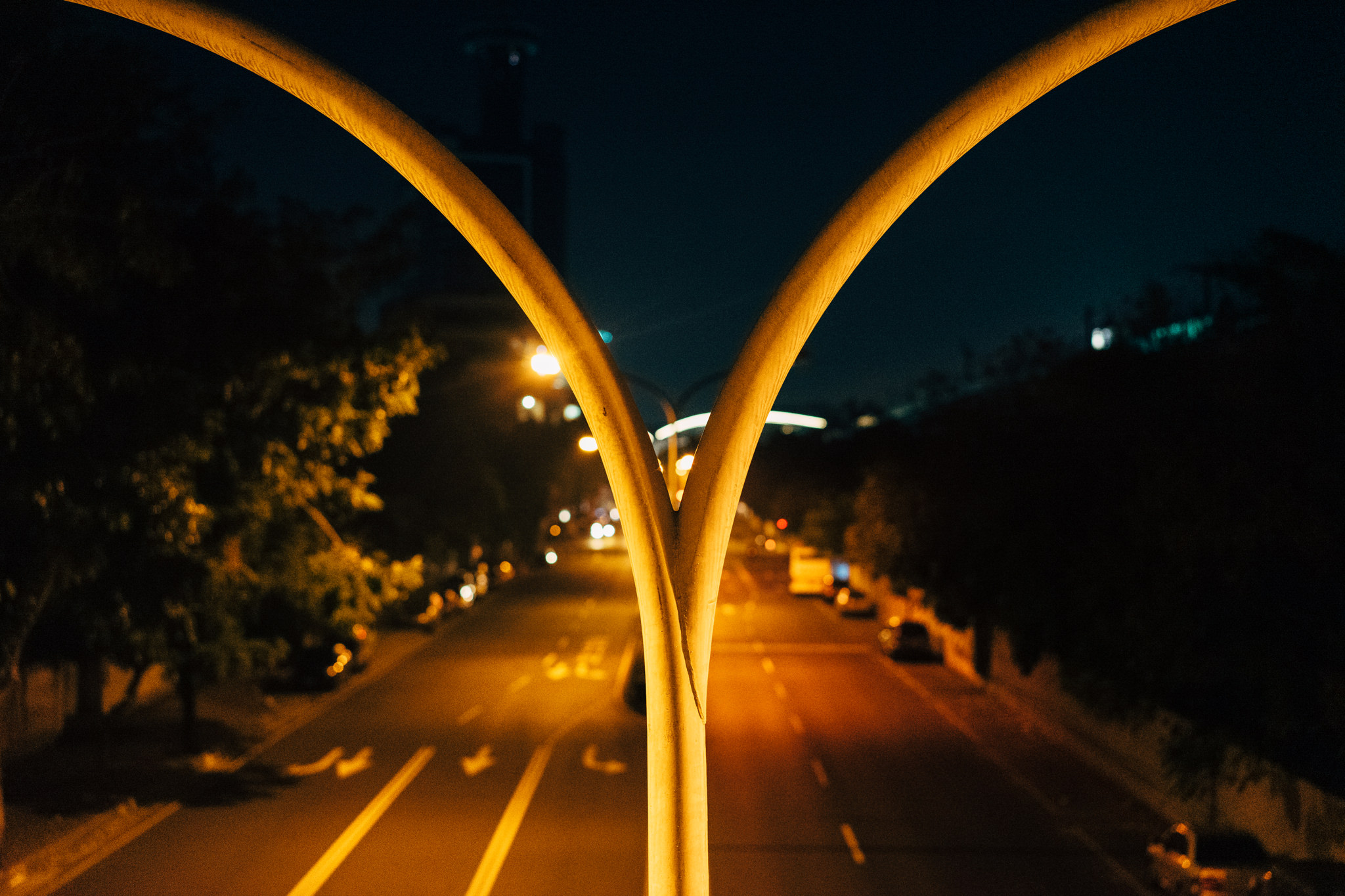 Nighttime view of a city street through a Y-shaped metal structure.