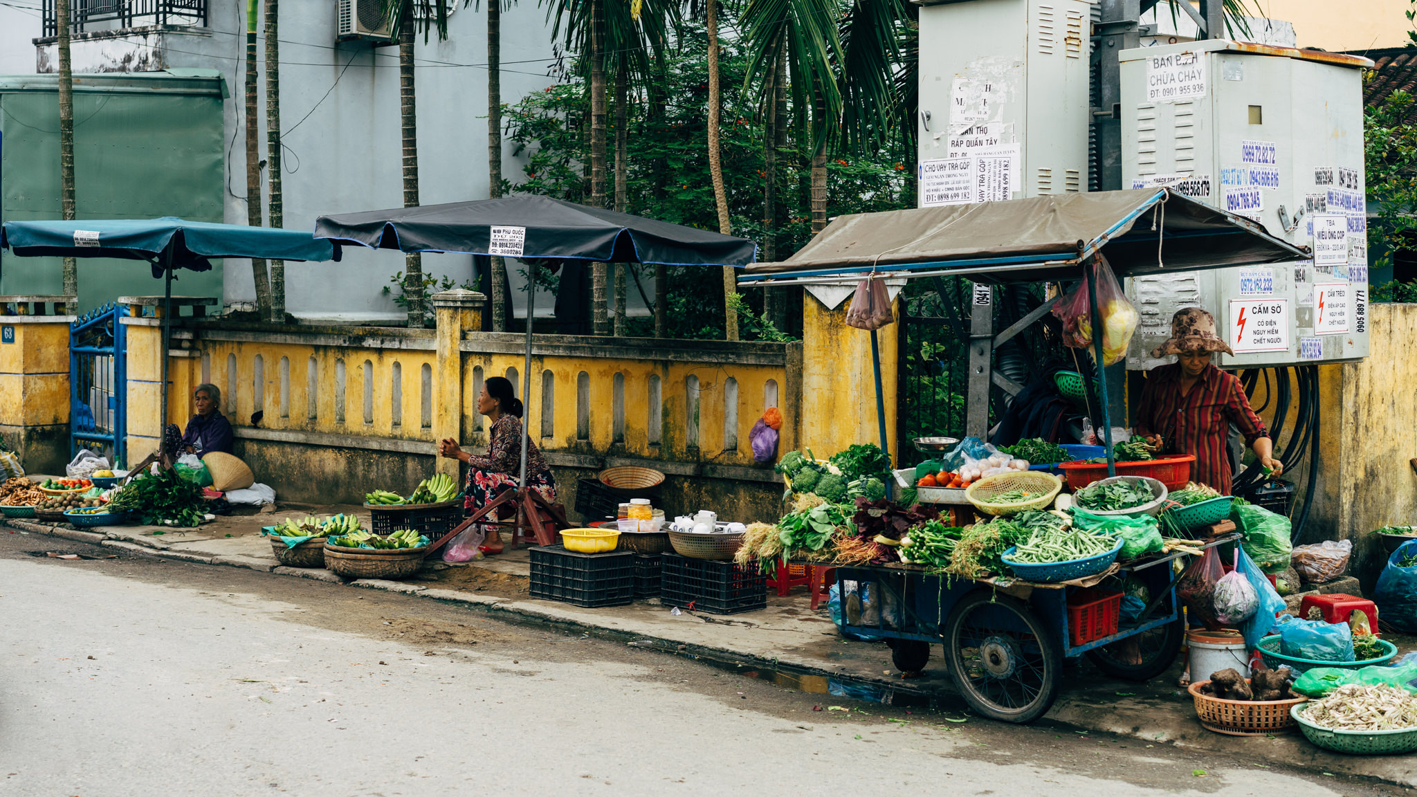 Three women selling produce at a roadside market.
