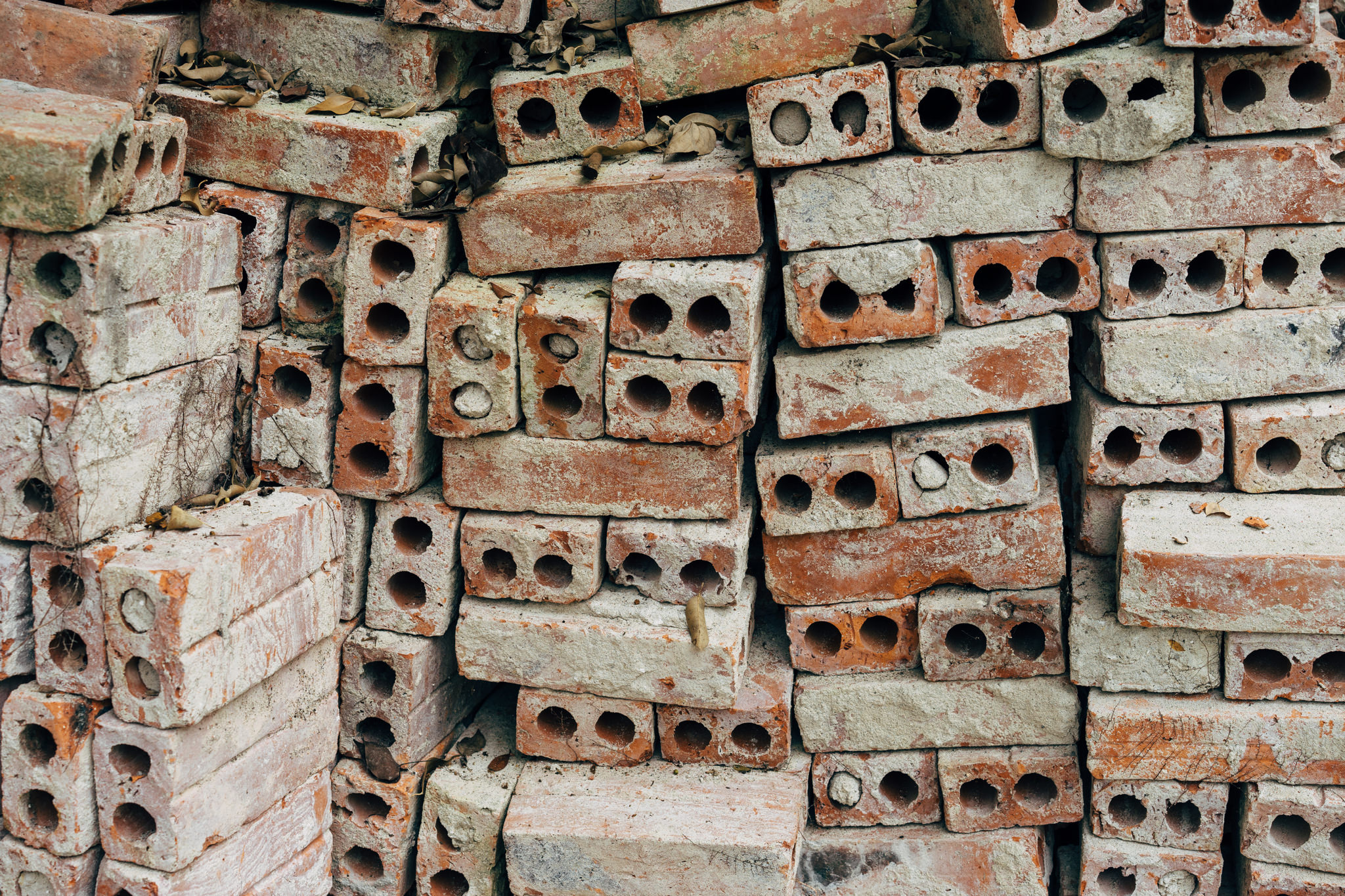 Pile of old, weathered bricks with holes.