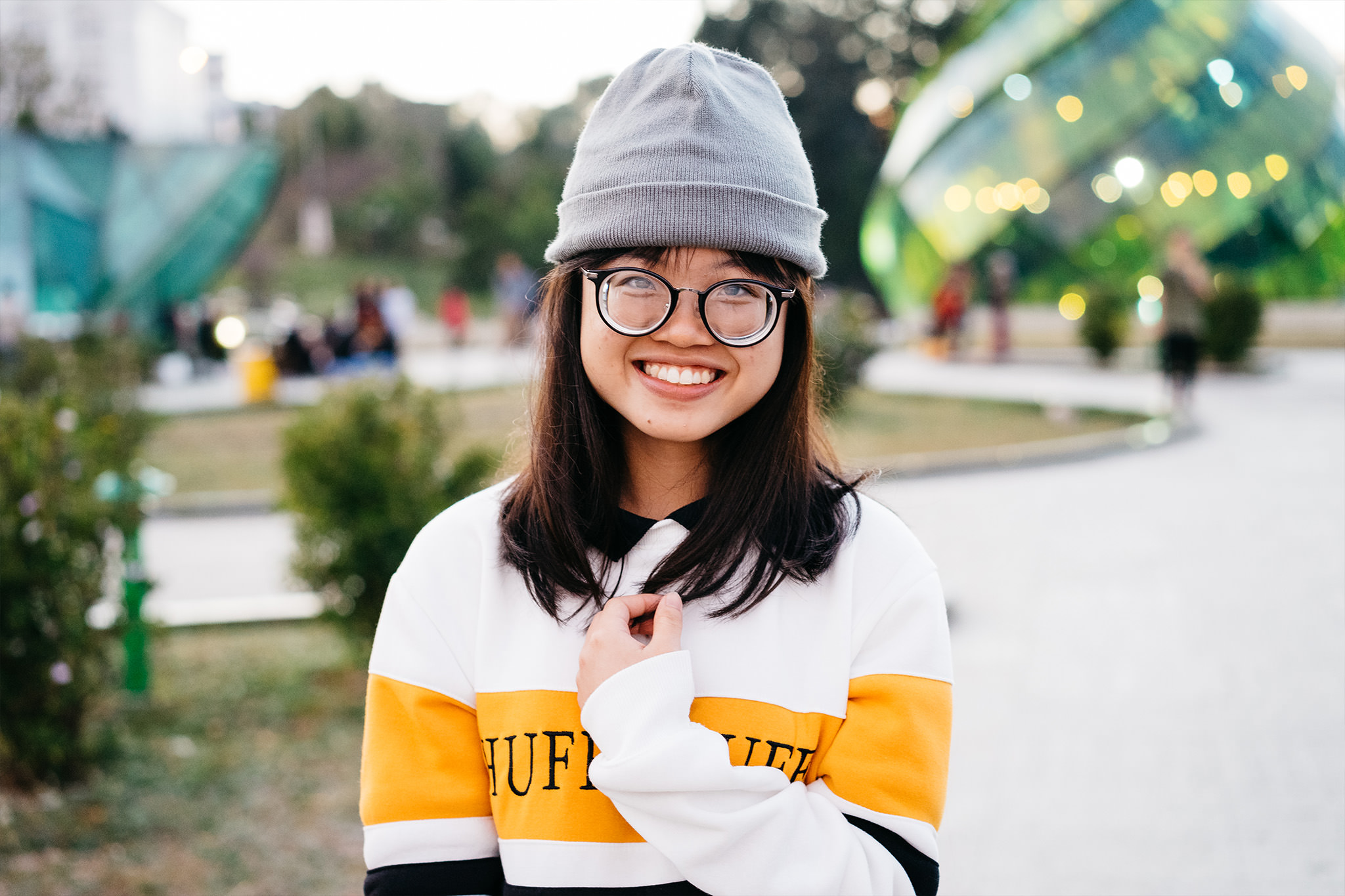 Smiling young woman wearing glasses and a gray beanie.