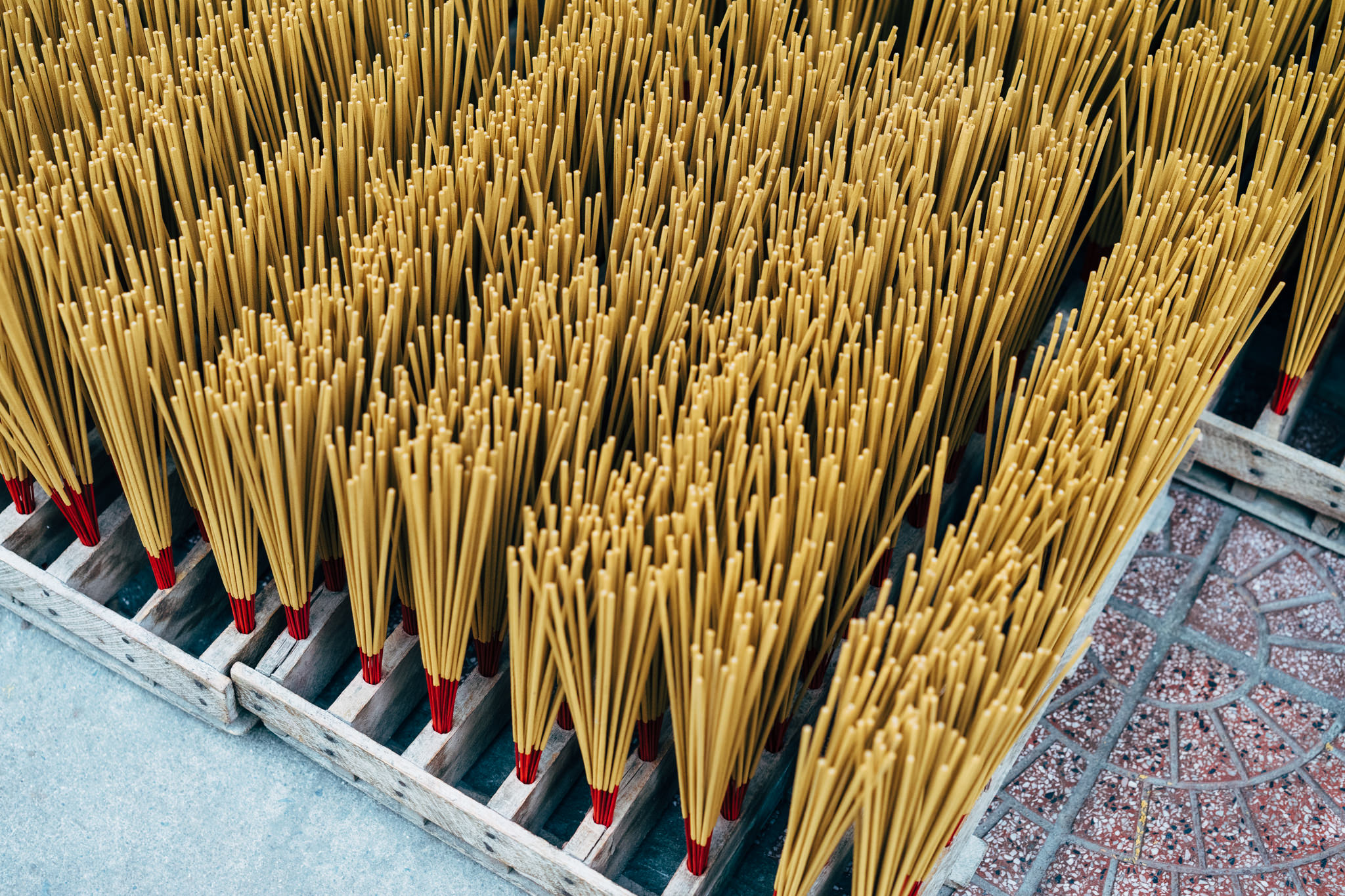 Many tan incense sticks bundled together in wooden crates.