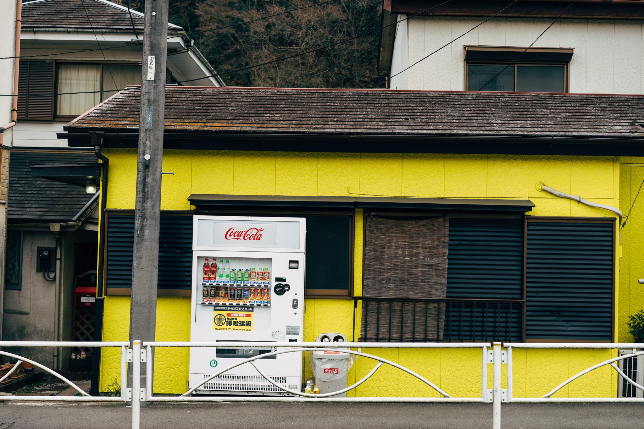 Coca-Cola vending machine in front of a yellow building.