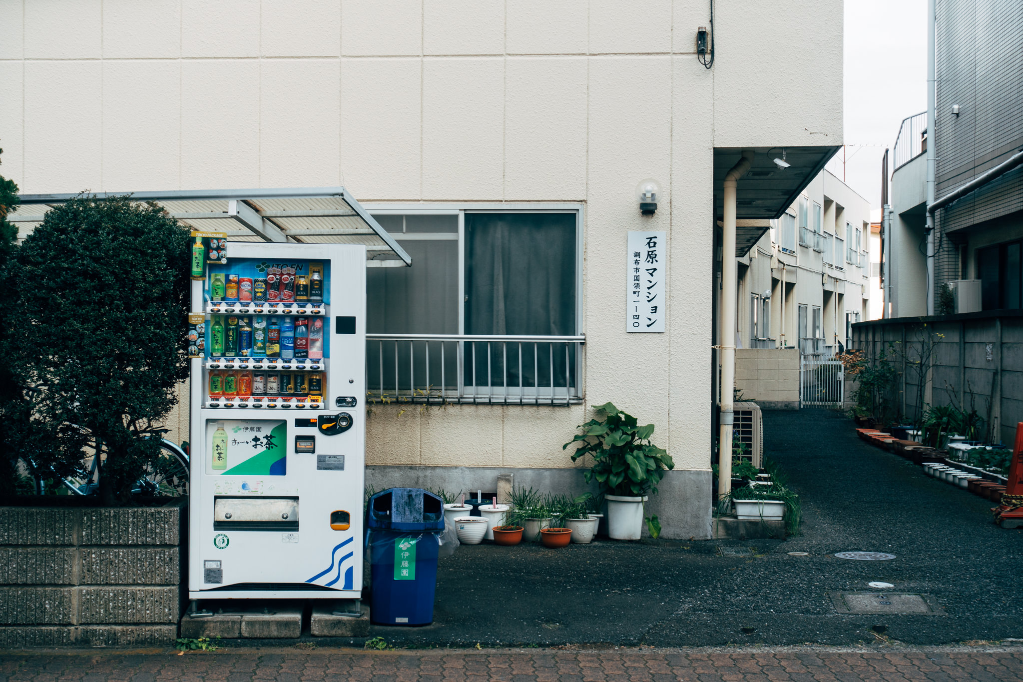 Japanese vending machine stocked with beverages, next to a building.