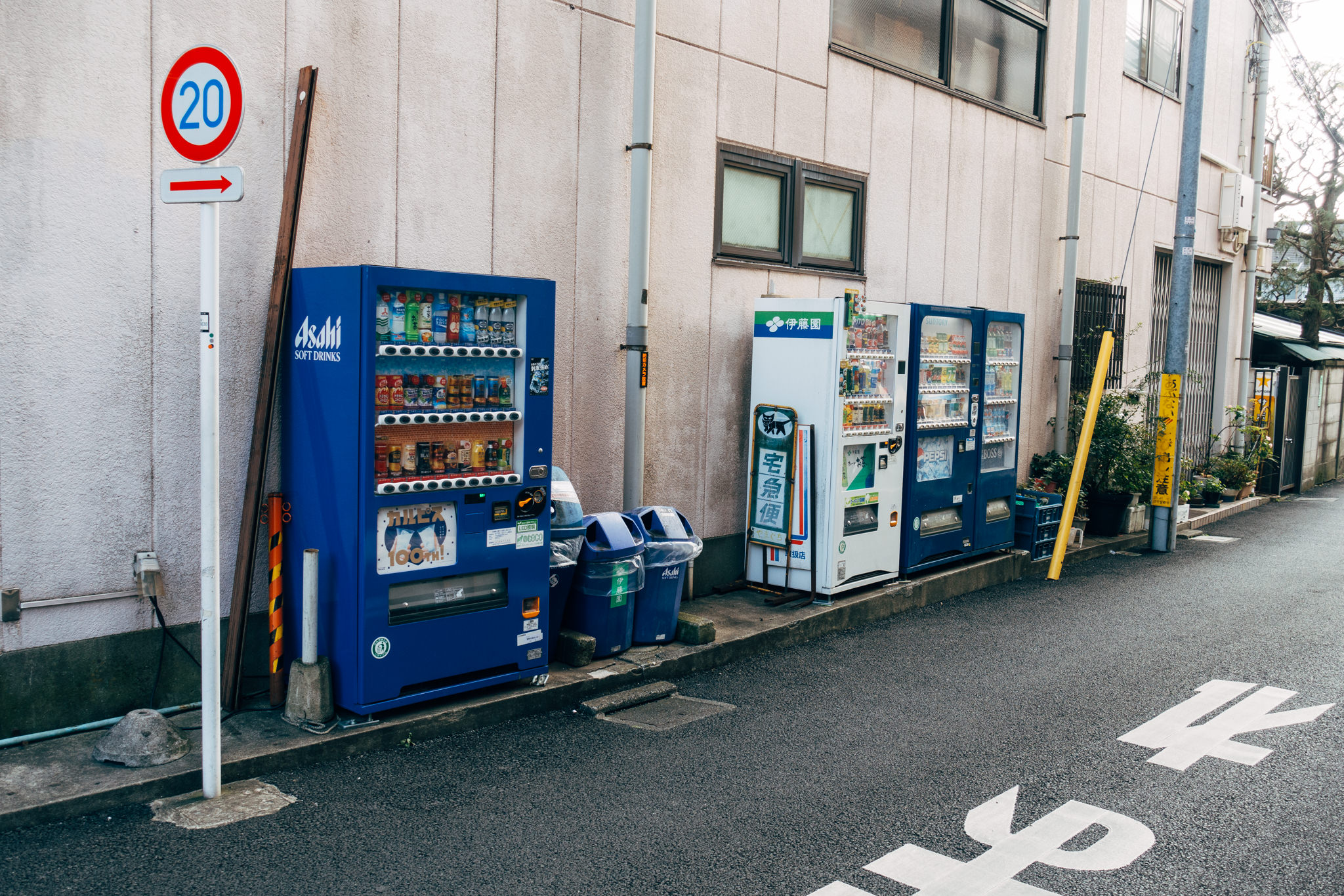 Two Japanese beverage vending machines and a 20 km/h speed limit sign.