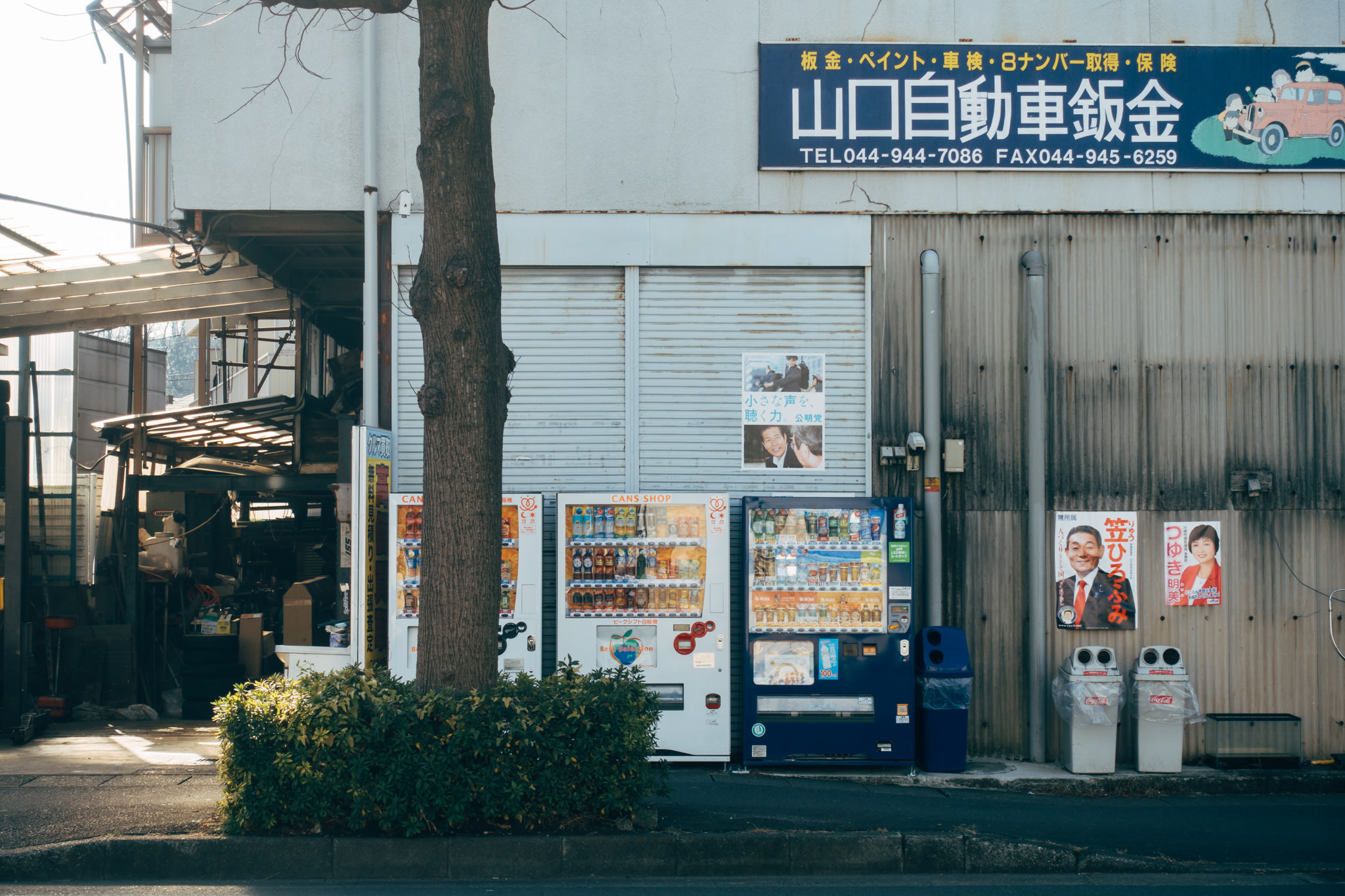 Three Japanese beverage vending machines outside a building.