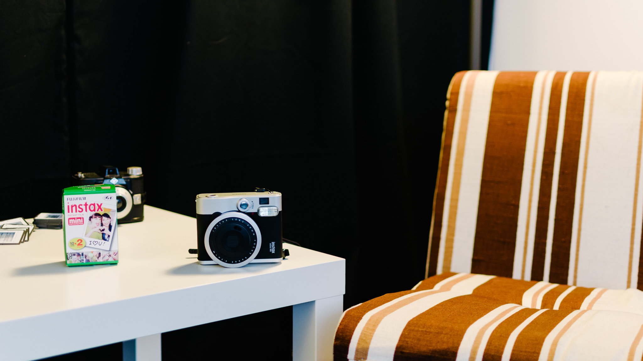 Fujifilm Instax Mini 90 camera and Instax Mini film on a white table.