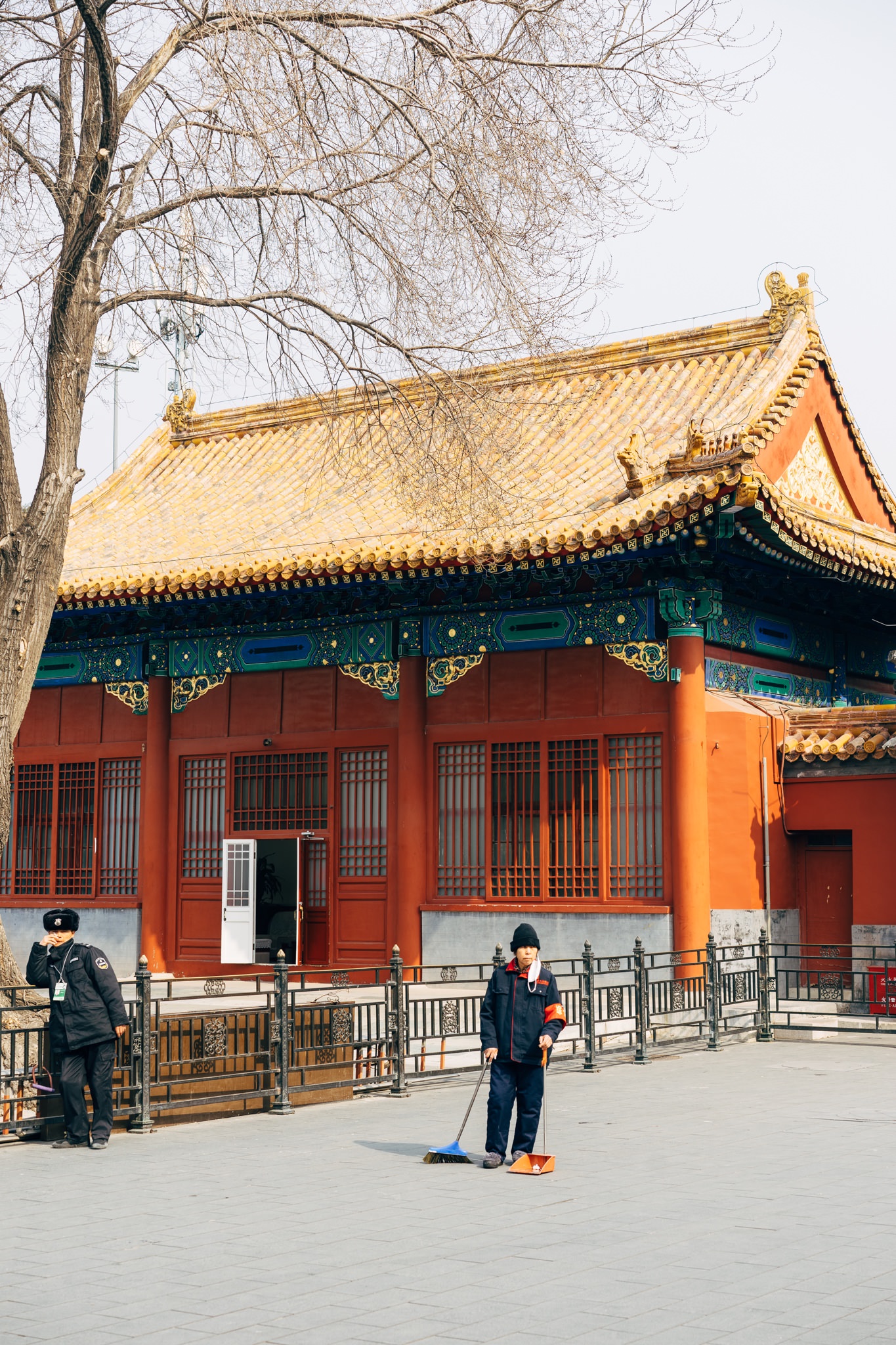Cleaning worker sweeping in front of a traditional Chinese building.