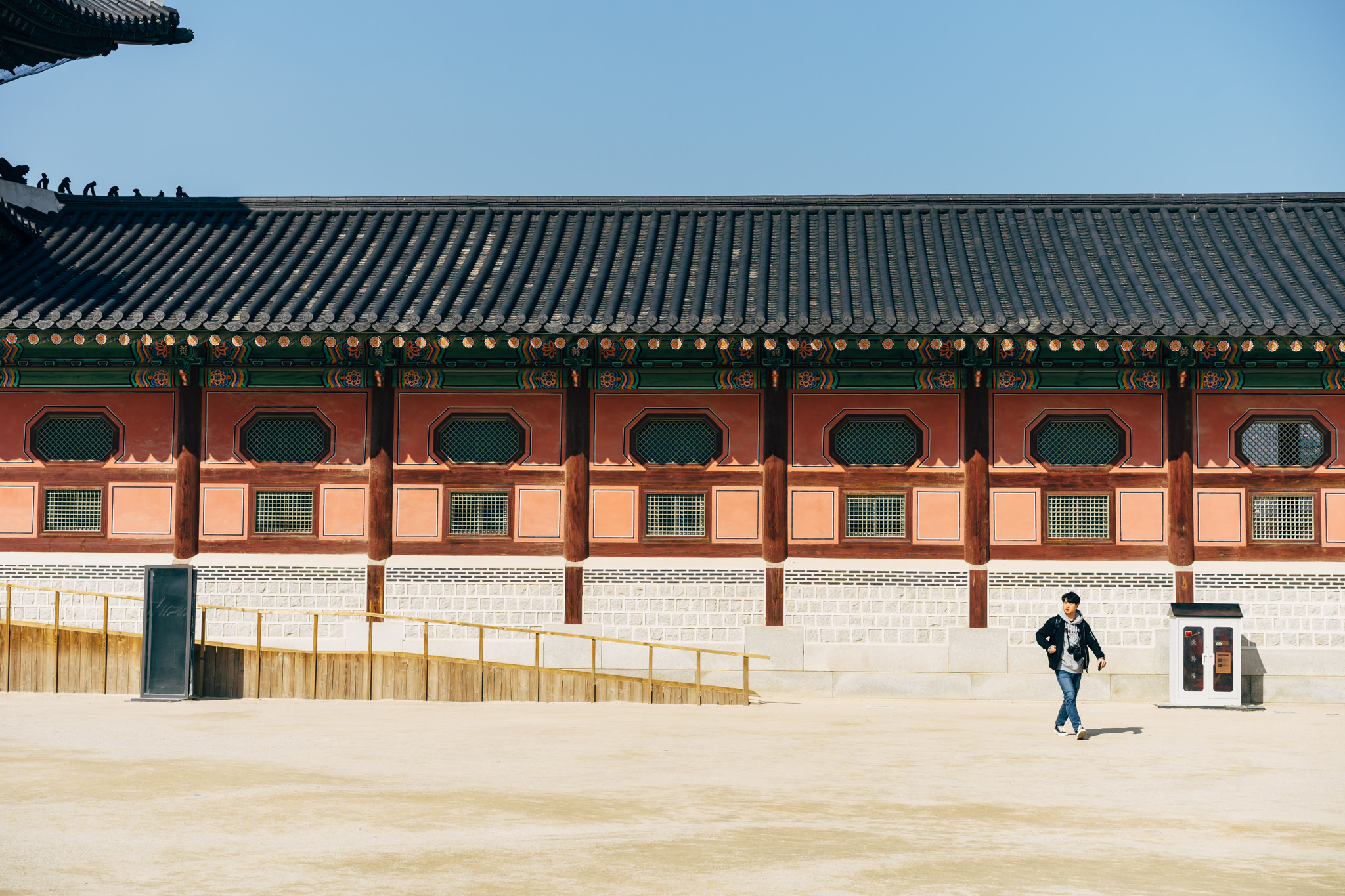 Person walking in front of Gyeongbokgung Palace building.