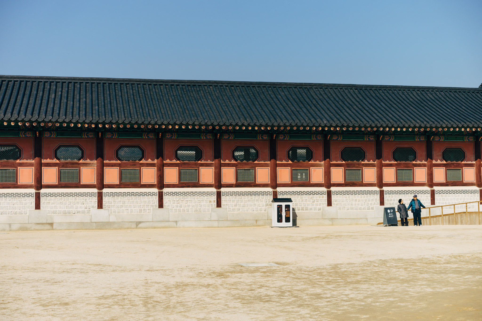 Gyeongbokgung Palace exterior with two people standing in front.