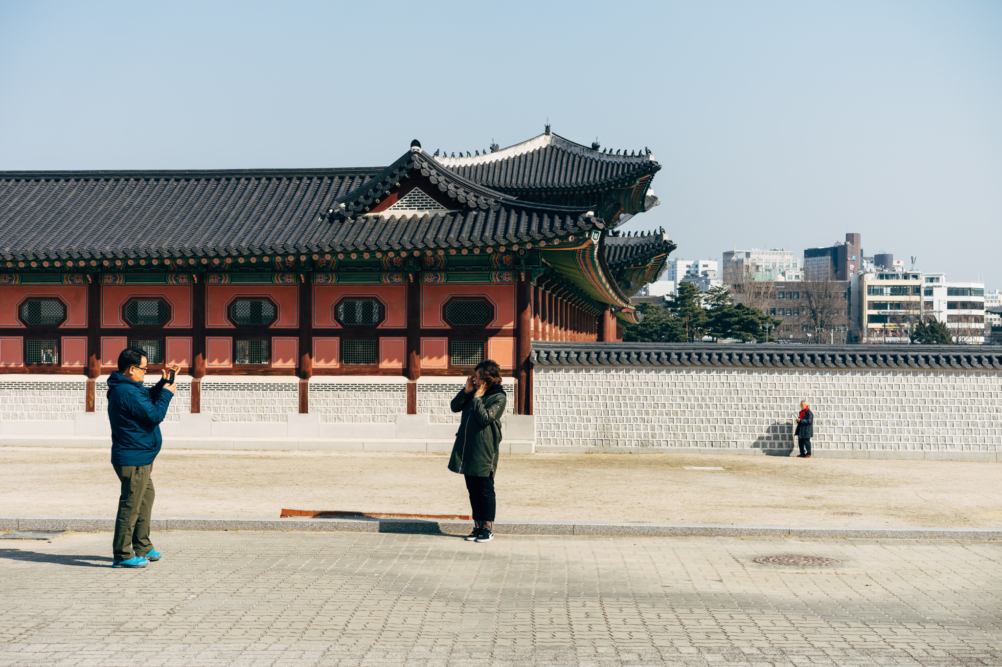 Two people near Gyeongbokgung Palace; one taking a photo, the other on a phone call.