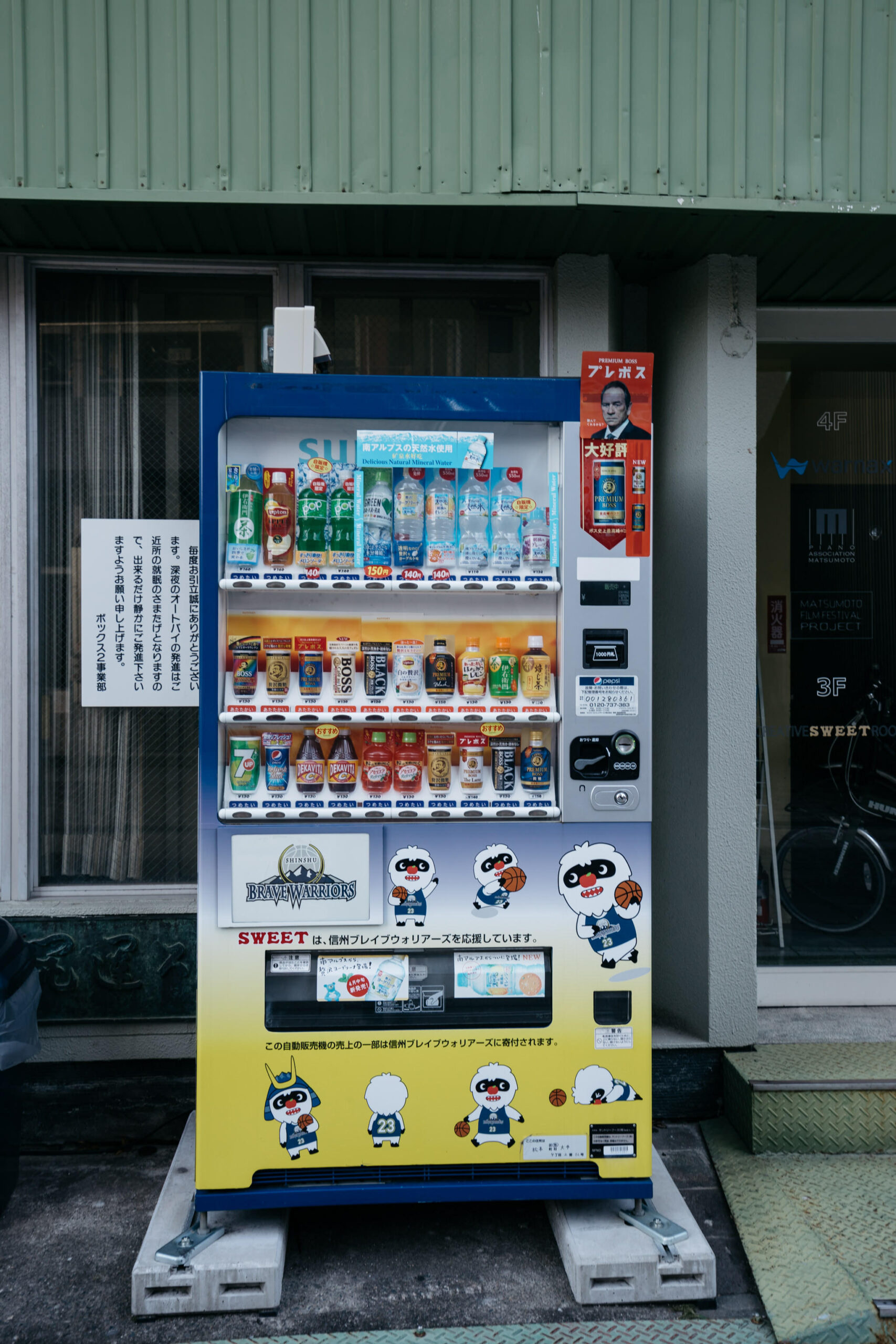 Japanese vending machine stocked with drinks, featuring Brave Warriors mascot branding.