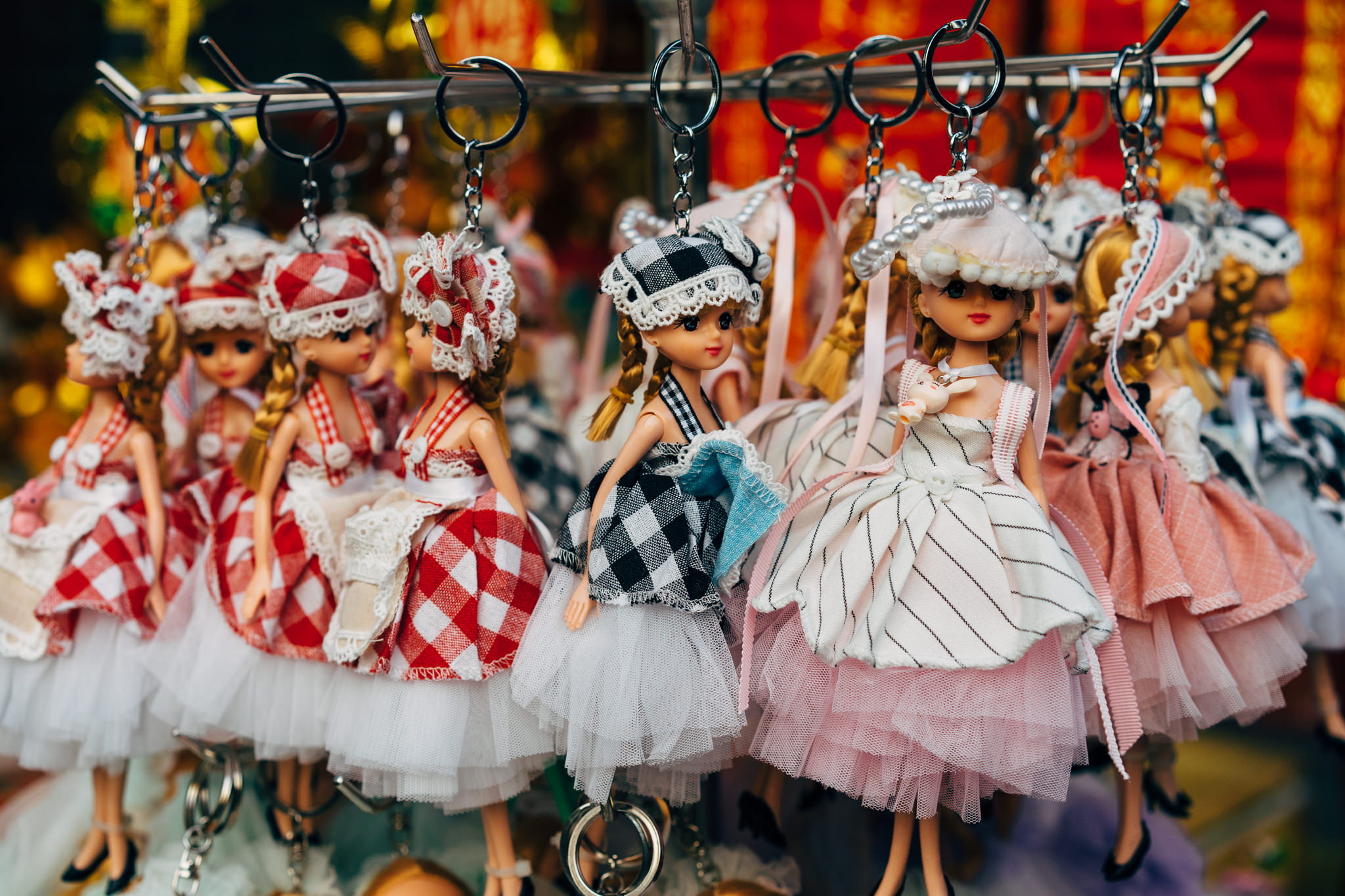 Several doll keychains on a display rack.