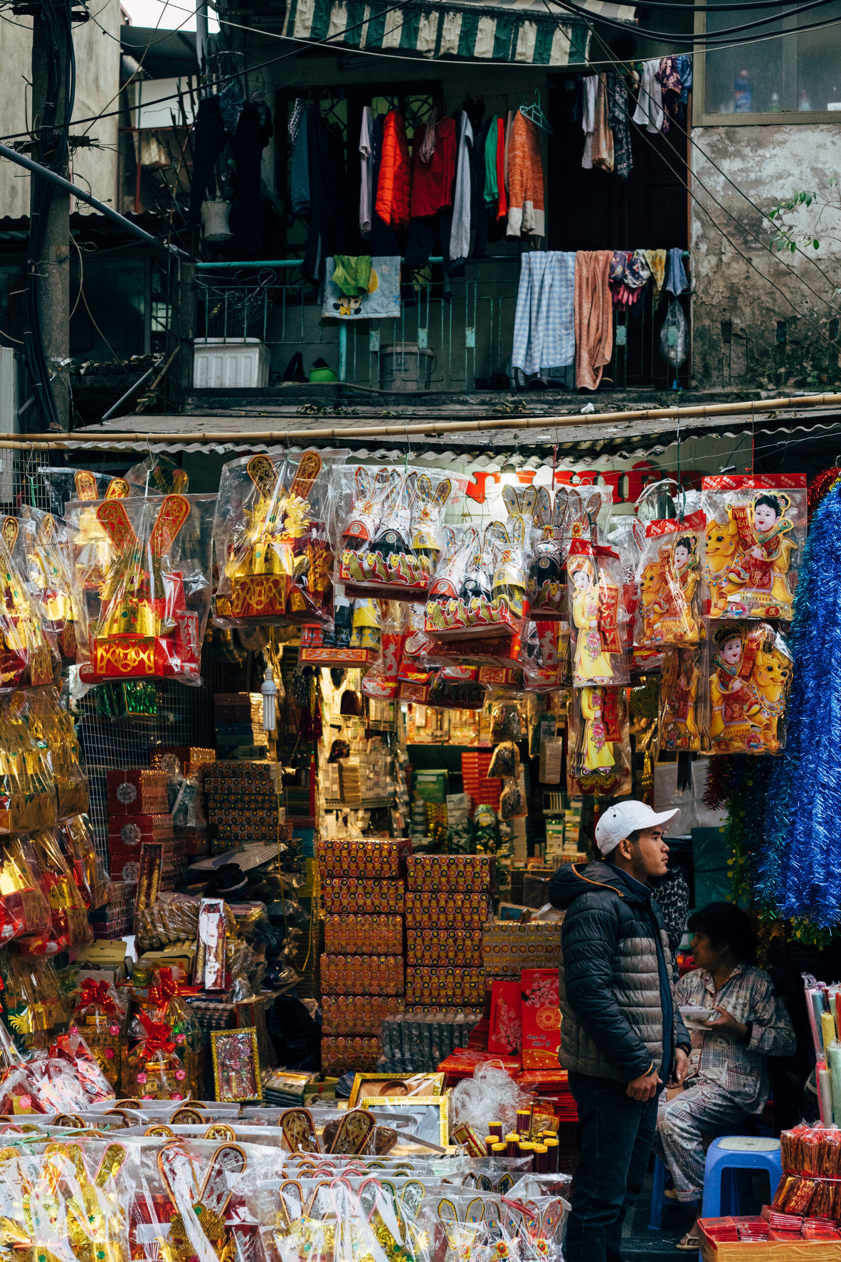 A street market stall overflowing with colorful, plastic-wrapped holiday decorations and gifts.