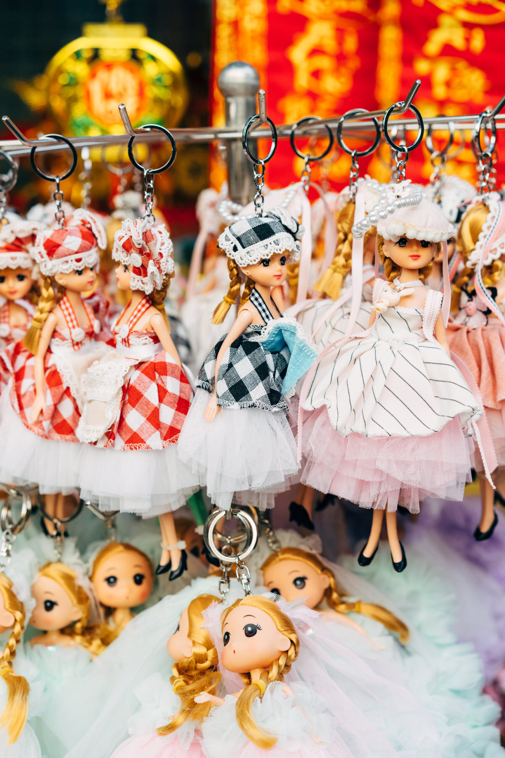 Several doll keychains on a display rack.