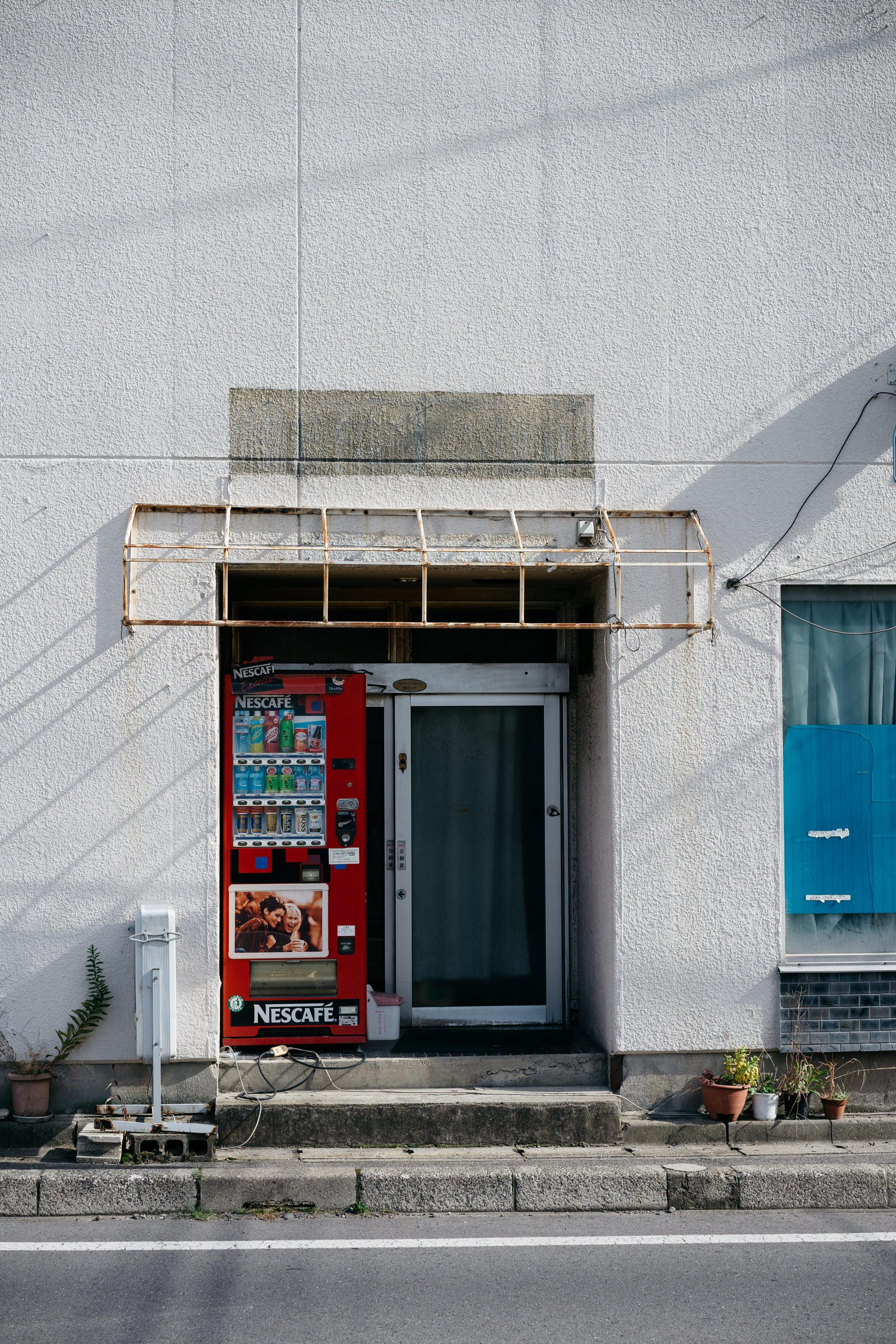 Red vending machine next to a building entrance.