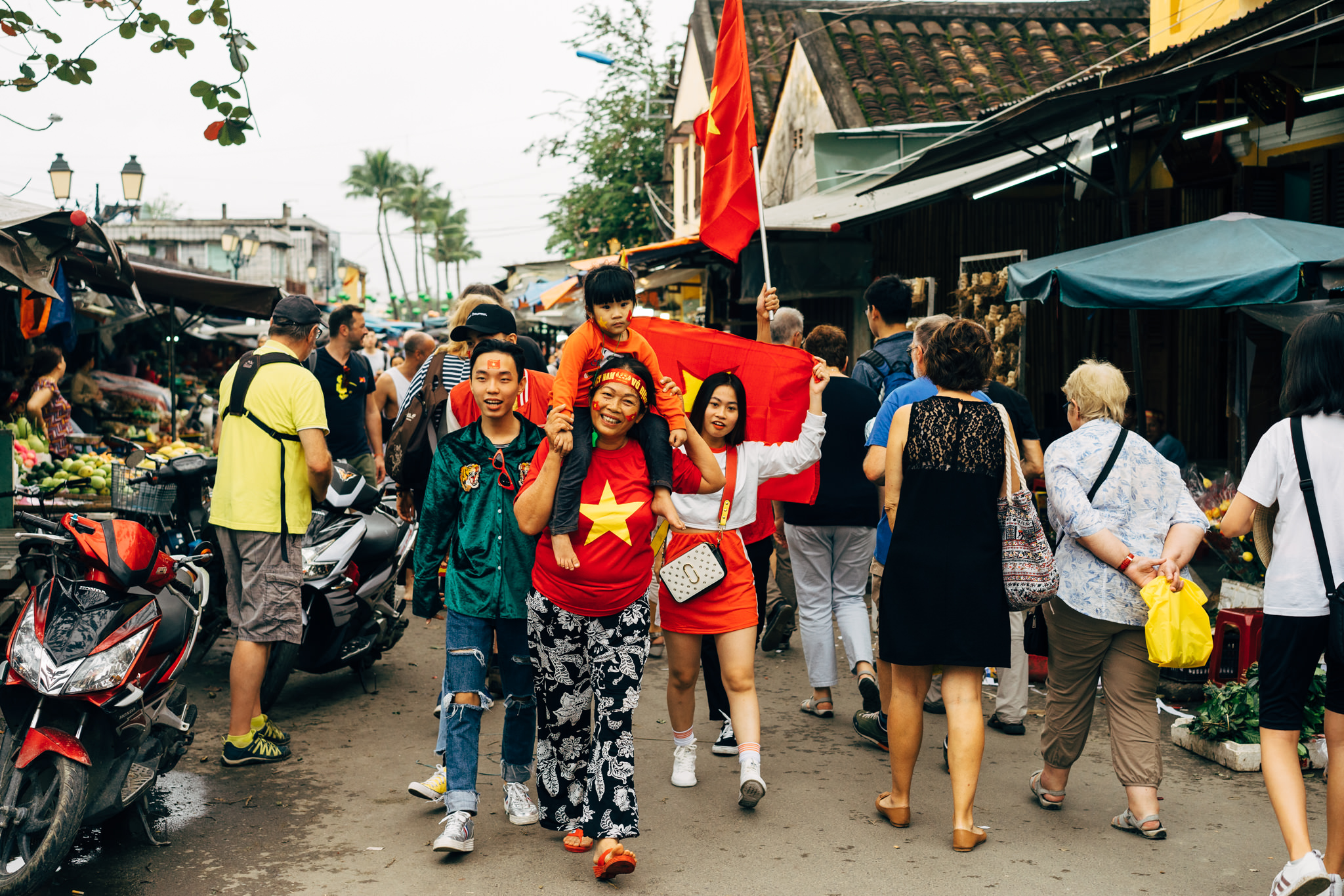 Vietnamese soccer fans celebrating in a market street.