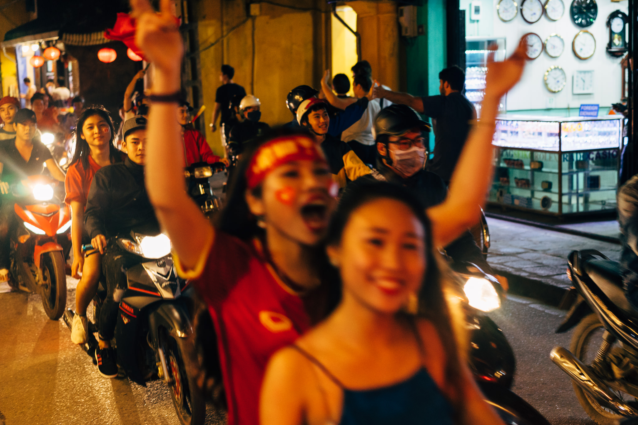 Vietnamese soccer fans celebrating in the street at night on motorbikes.