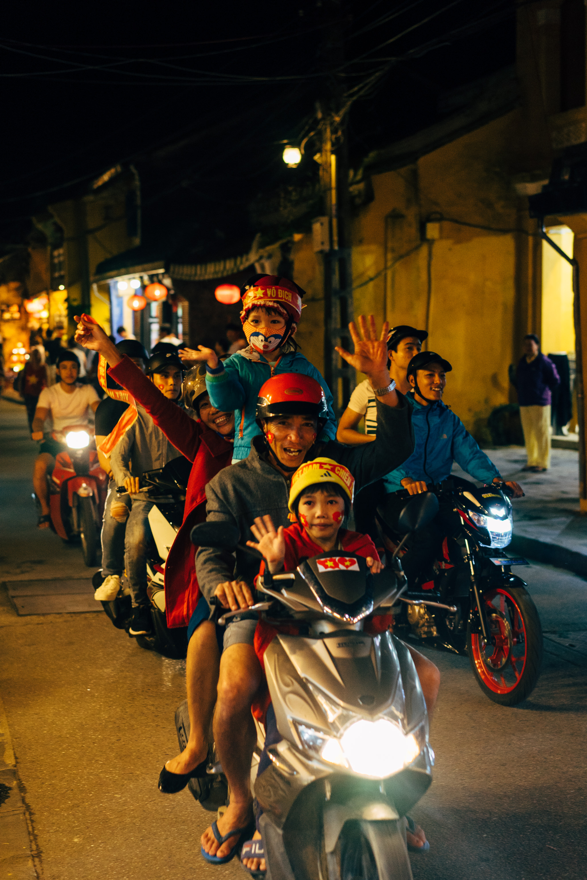 Vietnamese soccer fans riding on motorbikes at night, celebrating.
